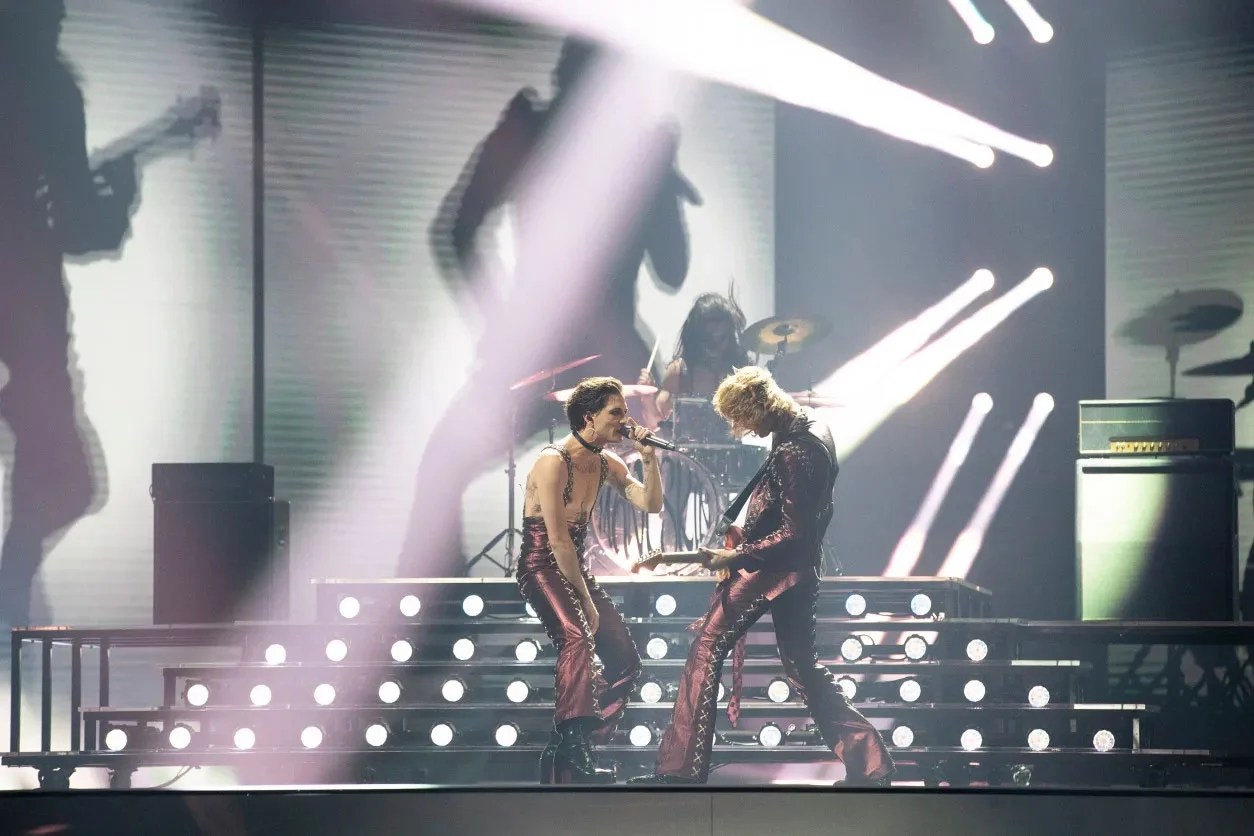 Cantante e chitarrista faccia a faccia davanti alla pedana della batteria illuminata – Måneskin all'Eurovision 2021, Rotterdam, Paesi Bassi – scenografia per concerti