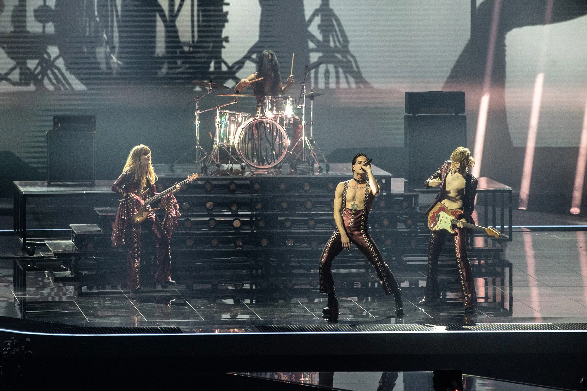 Måneskin in concerto sul palco, la batteria rialzata su gradini illuminati alle loro spalle – Måneskin all'Eurovision 2021, Rotterdam, Paesi Bassi – scenografia per concerti