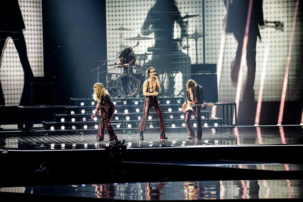 La band sul palco davanti a un fondale con l'enorme sagoma del batterista – Måneskin all'Eurovision 2021, Rotterdam, Paesi Bassi – scenografia per concerti
