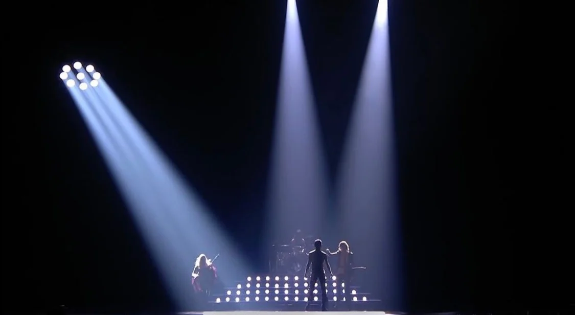Palco buio illuminato solo da tre riflettori bianchi sulla band – Måneskin all'Eurovision 2021, Rotterdam, Paesi Bassi – scenografia per concerti