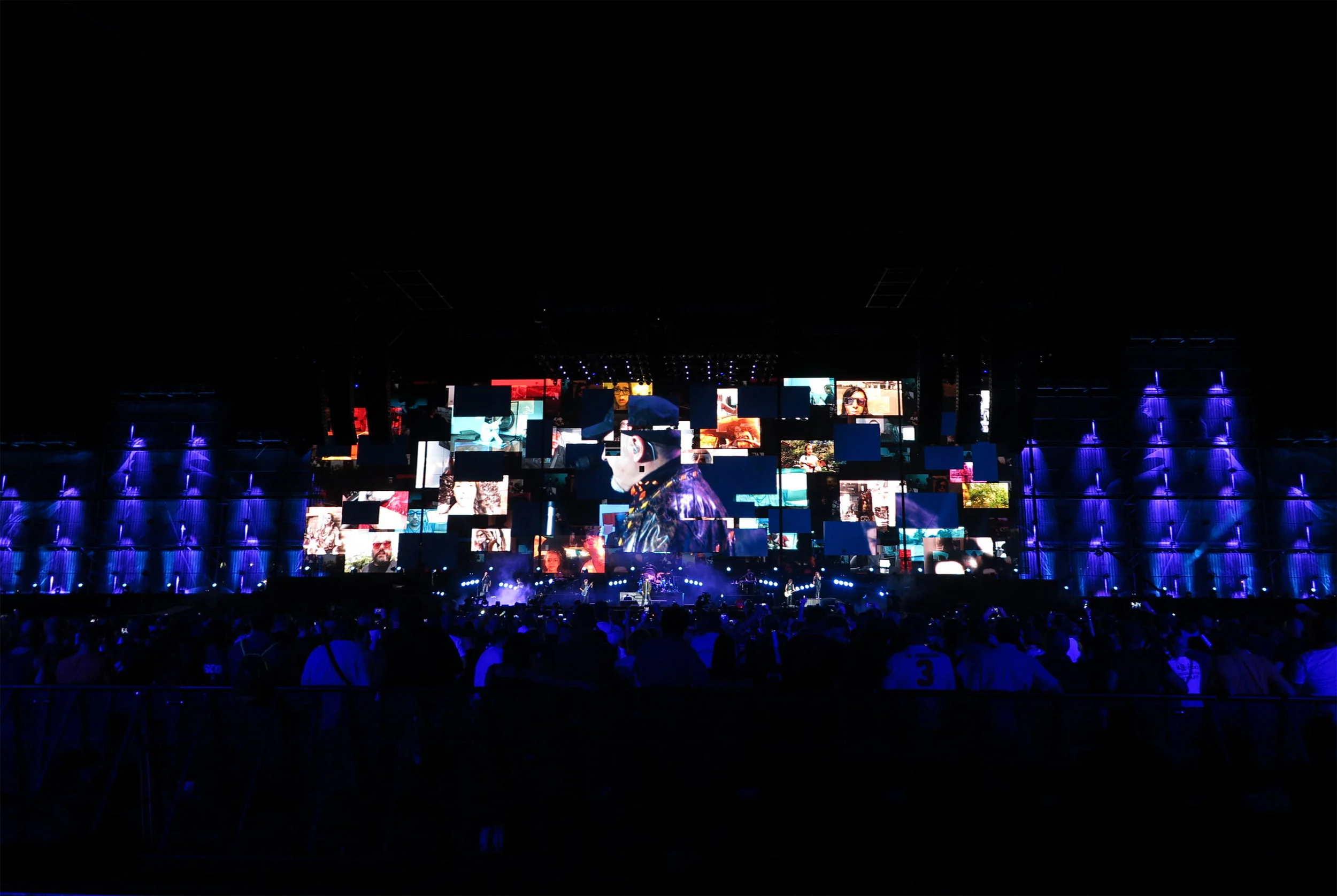 Vista notturna del palco del Modena Park: un mosaico di schermi video tra torri illuminate di viola davanti al pubblico – Vasco Rossi Modena Park, Italia, 2017 – scenografia per concerti