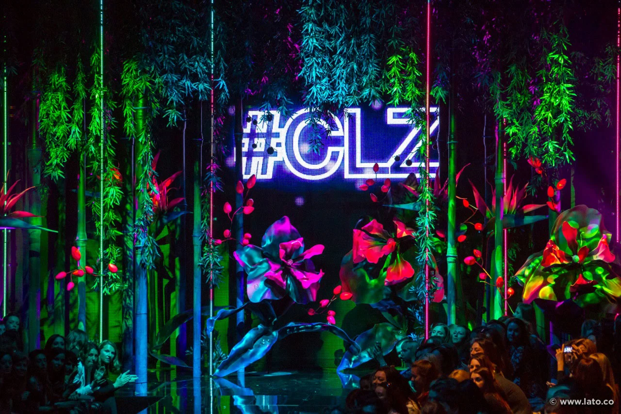 Dettaglio della scenografia con l'insegna al neon #CLZ tra verde pendente, fiori giganti e tubi al neon – Collezione Calzedonia SS15, Italia, 2015 – scenografia per sfilate
