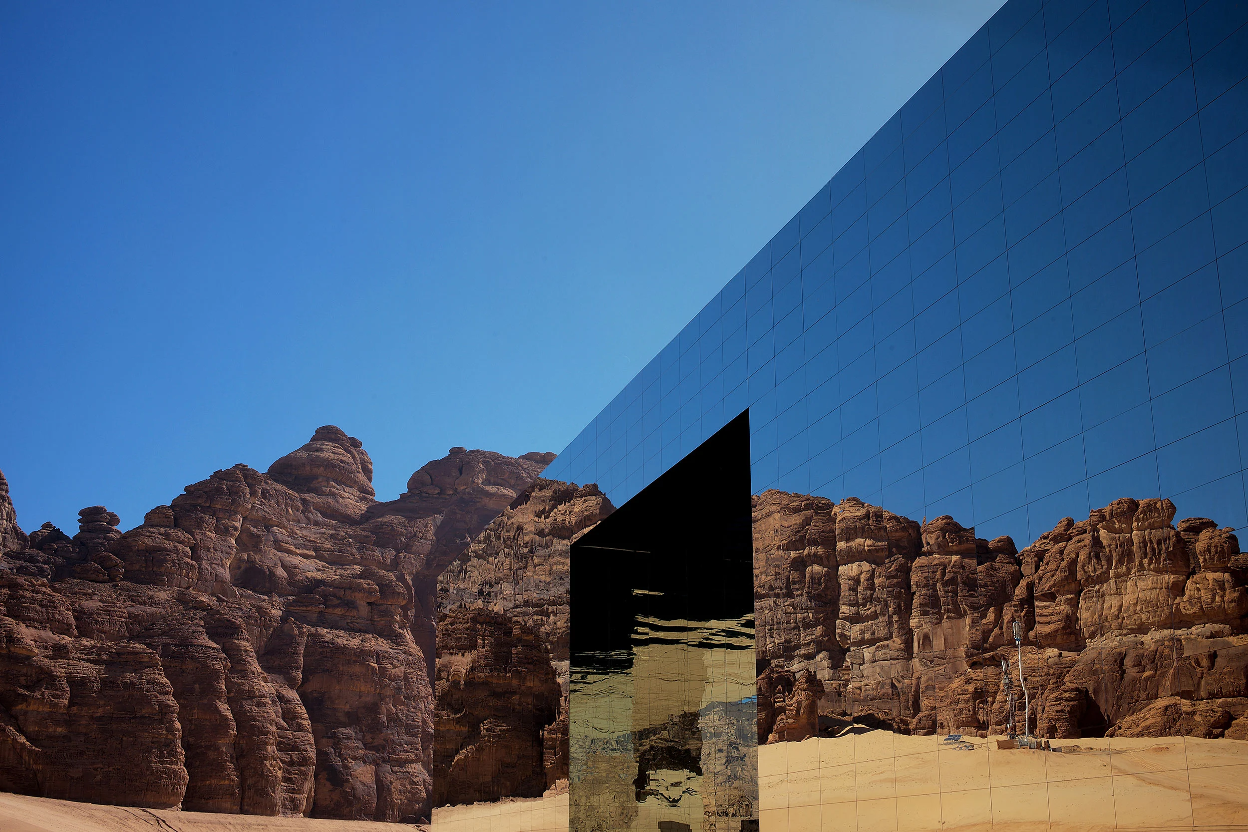 Spigolo dell'edificio a specchio con il taglio dell'ingresso, che riflette falesie di arenaria rossa – Maraya Concert Hall, AlUla, Arabia Saudita, 2019 – architettura