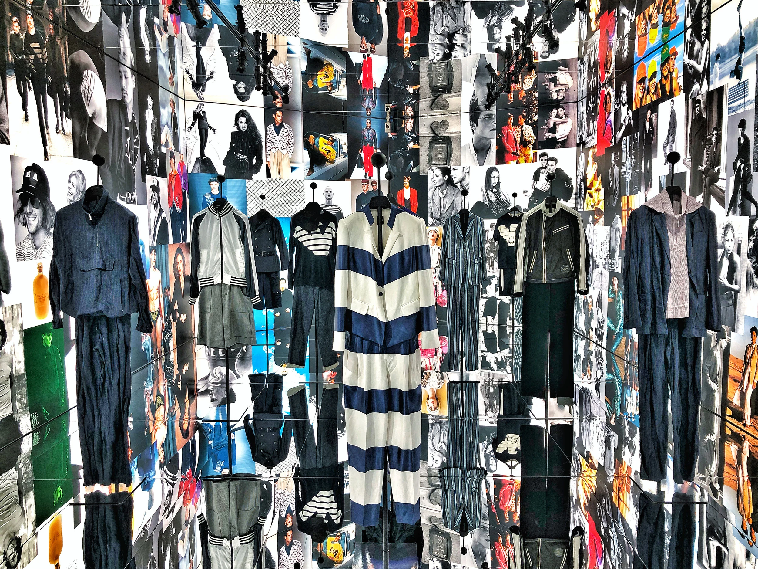 Capi su supporti in una stanza a specchio rivestita dal pavimento al soffitto di fotografie di moda – Emporio Armani The Way We Are, Milano, Italia, 2020 – allestimento espositivo
