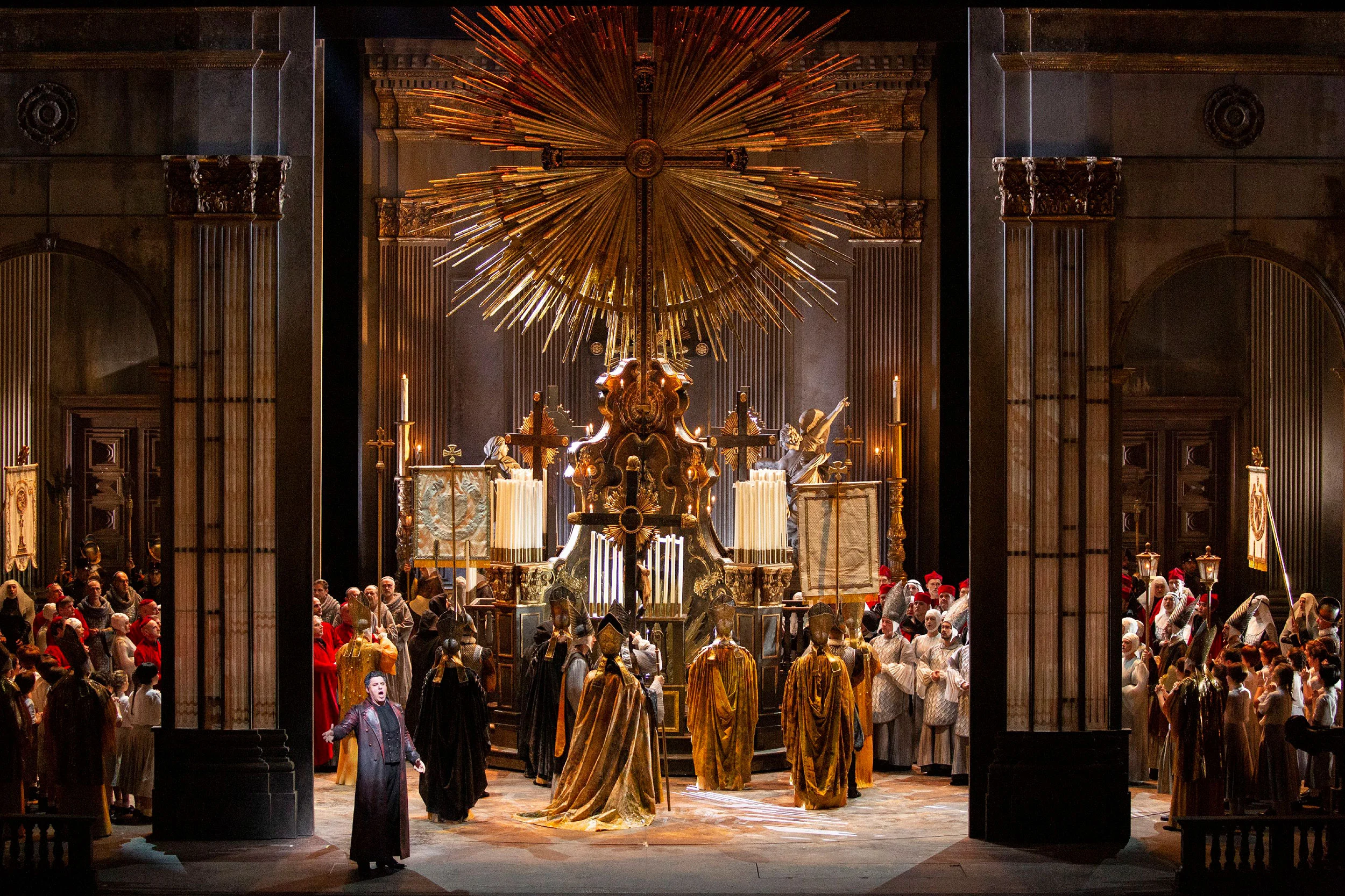 Scenografia di una chiesa con un'imponente croce dorata a raggiera sopra l'altare, folle di religiosi ai due lati – Tosca al Teatro alla Scala, Milano, Italia, 2019 – scenografia d'opera