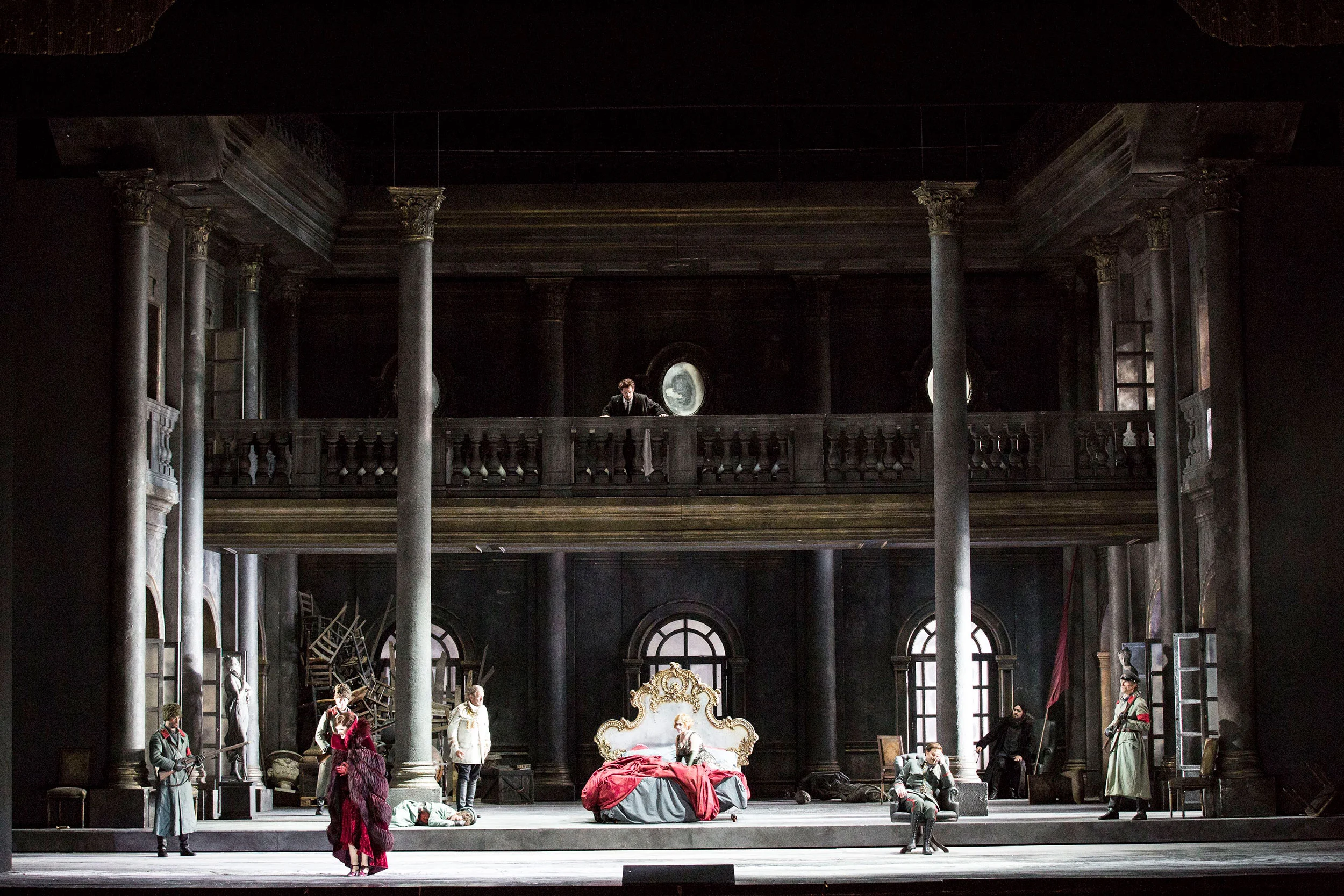 Scenografia di un interno di palazzo con colonne, una galleria superiore e un letto dorato al centro, artisti intorno – Tamerlano al Teatro alla Scala, Milano, Italia, 2017 – scenografia d'opera