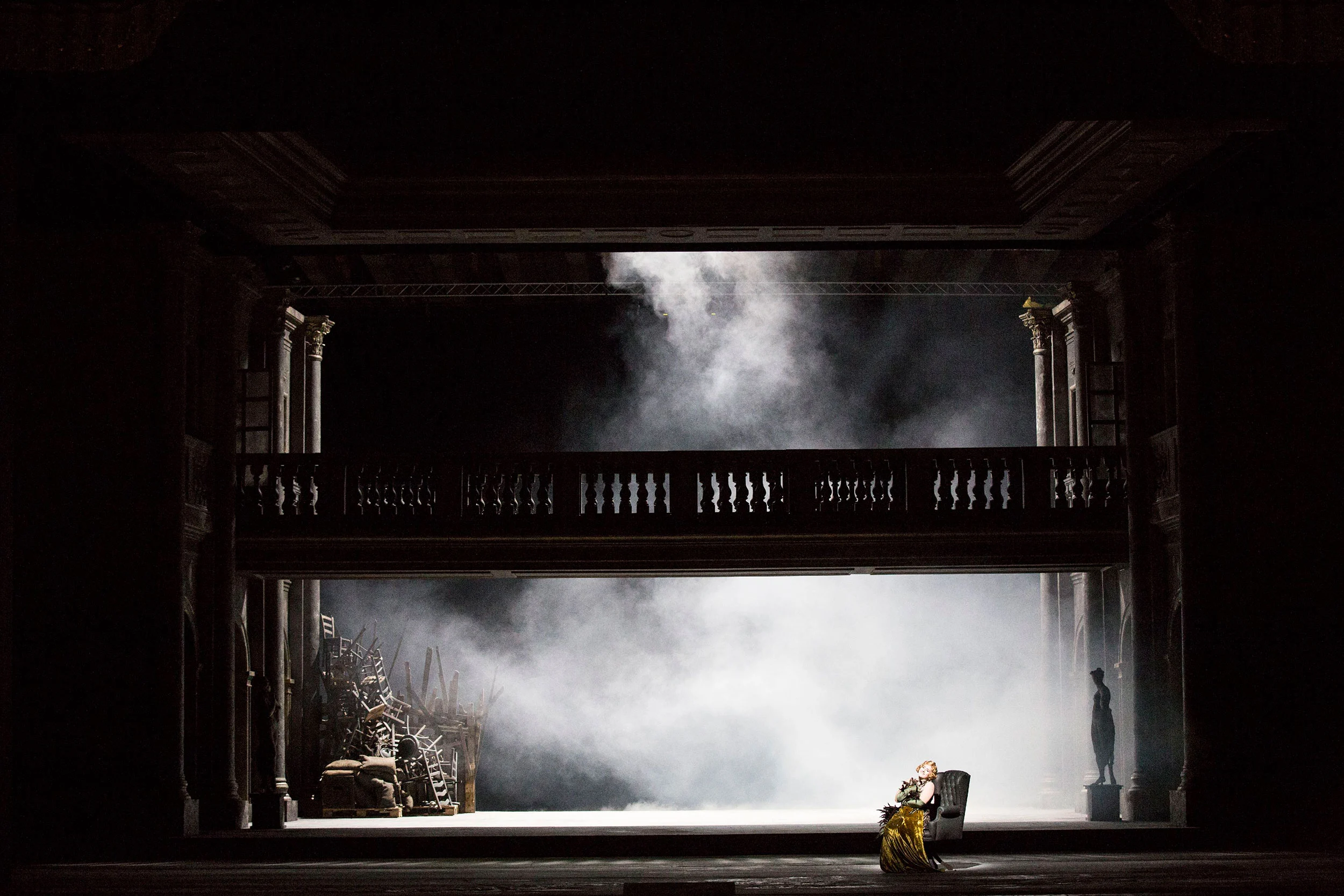 Palco buio con una galleria a balaustra e fumo, una figura solitaria seduta in poltrona in un cono di luce – Tamerlano al Teatro alla Scala, Milano, Italia, 2017 – scenografia d'opera