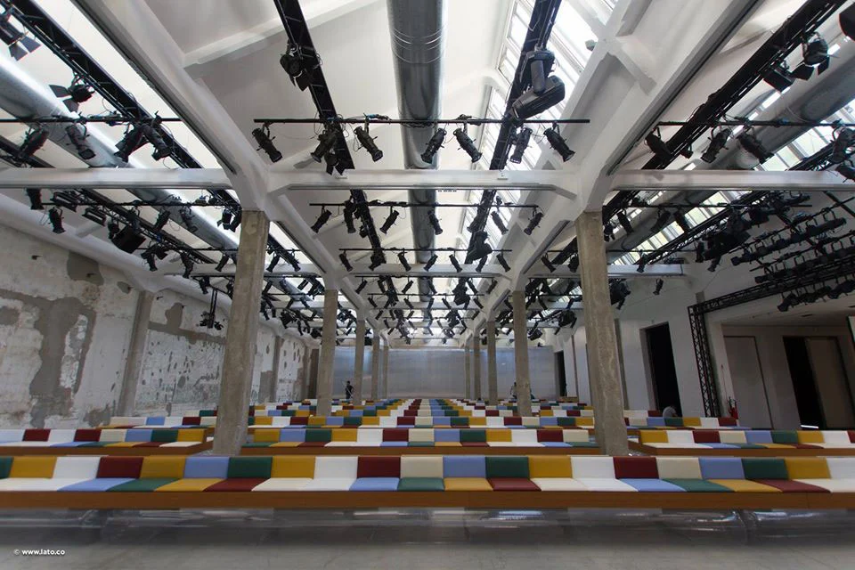 Location di una sfilata con lunghe panche a strisce colorate sotto file di riflettori e capriate bianche del tetto – Marni Ready-to-Wear Primavera 2017, Milano, Italia – scenografia per sfilate