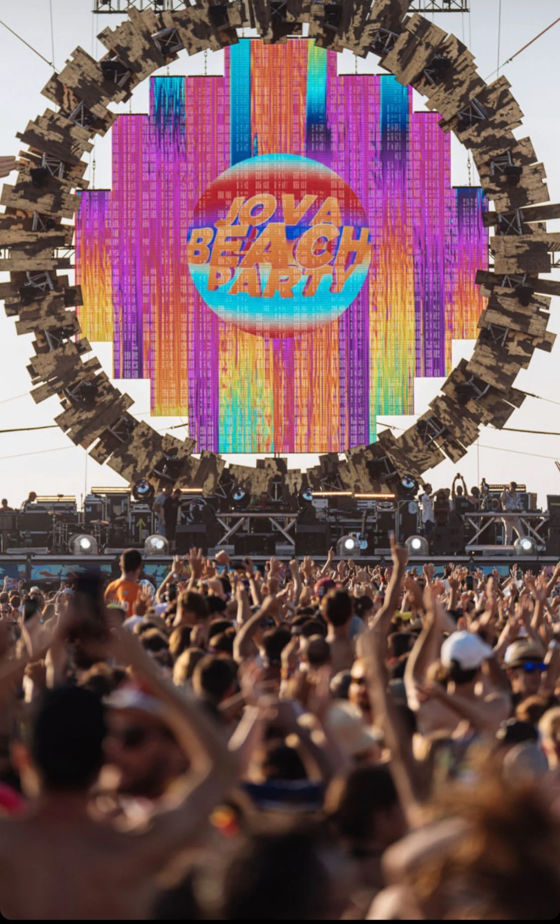 Pubblico a braccia alzate davanti allo schermo incorniciato dall'anello con il logo del Jova Beach Party – Jova Beach Party 2019, Italia – scenografia per concerti