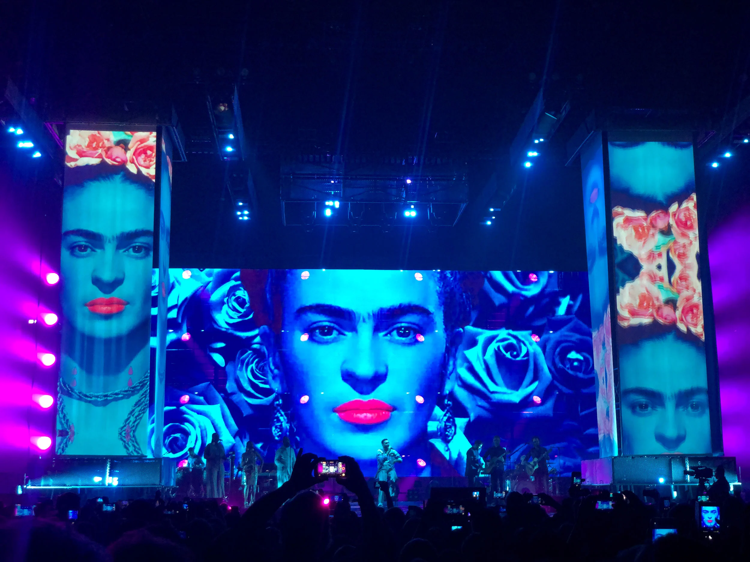 Marco Mengoni sul palco sotto schermi con il ritratto di una donna, labbra rosse e rose blu – Marco Mengoni Atlantico Tour 2019, Italia – scenografia per concerti
