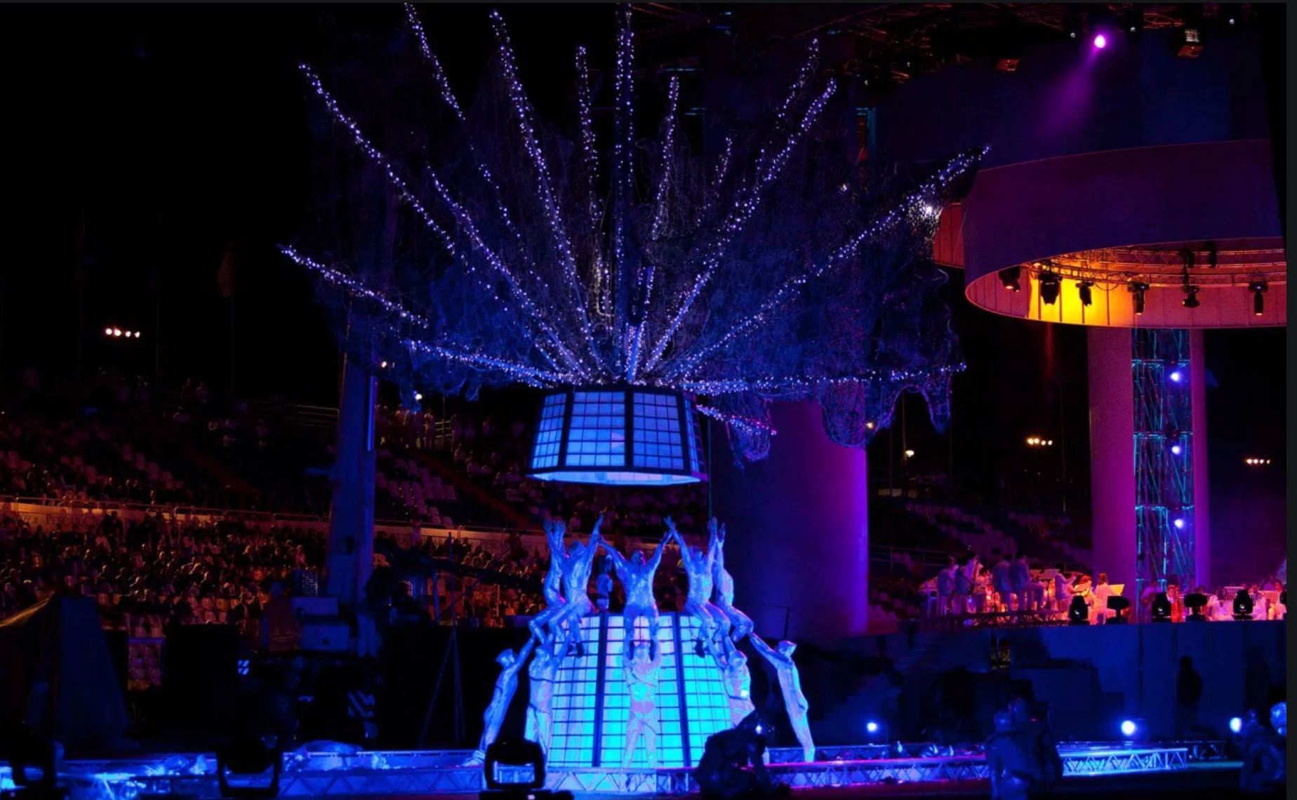 Acrobati in bianco in posa sotto una lanterna luminosa coronata da rami di luci bianche – Cerimonia di apertura dei Giochi del Mediterraneo Pescara 2009, Italia, 2019 – progettazione di eventi