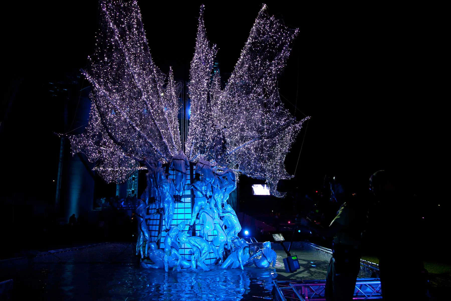 Albero scultoreo di figure intrecciate con rami di luci bianche, illuminato di blu di notte – Cerimonia di apertura dei Giochi del Mediterraneo Pescara 2009, Italia, 2019 – progettazione di eventi