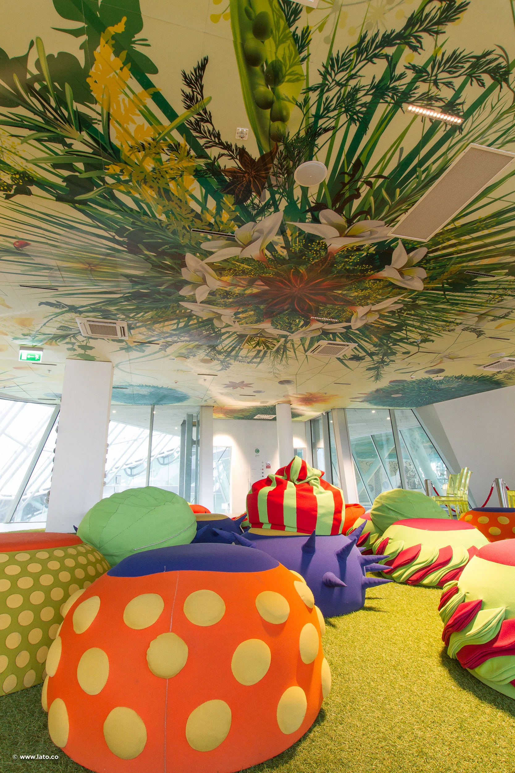 Sala giochi con una gigantesca chioma vegetale dipinta sul soffitto e sedute morbide a forma di frutta su moquette verde – Padiglione Italia all'Expo 2015, Milano, Italia – allestimento espositivo