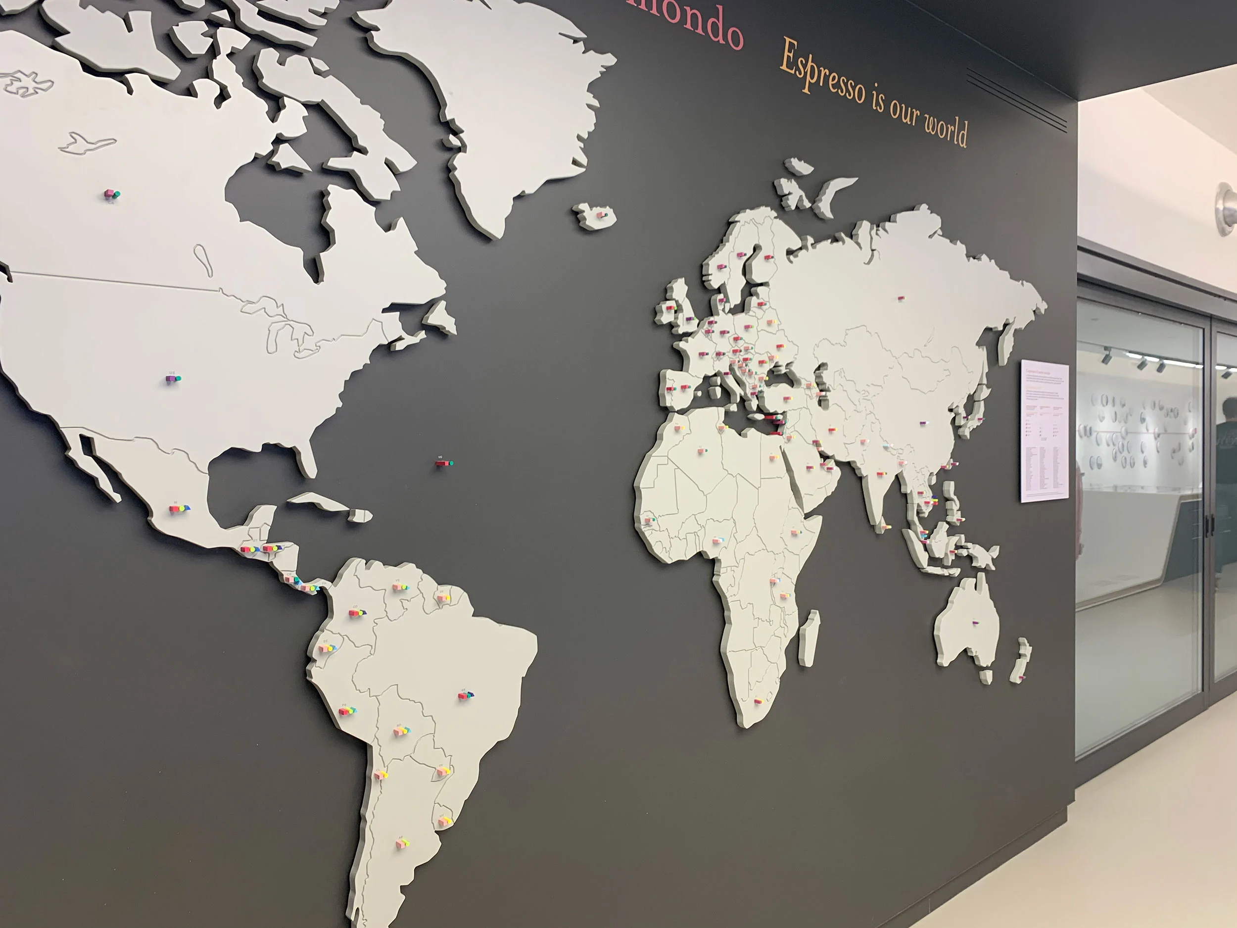 Mappa del mondo a tutta parete con continenti bianchi in rilievo e la scritta Espresso is our world – La Marzocco Accademia del Caffè Espresso, Firenze, Italia, 2018 – interior design