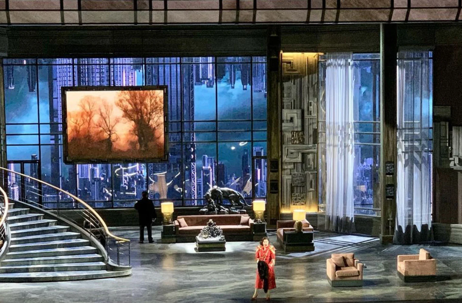 Scenografia di un attico di lusso con divani, un'ampia scalinata e una parete vetrata su uno skyline notturno – Macbeth al Teatro alla Scala, Milano, Italia, 2021 – scenografia d'opera