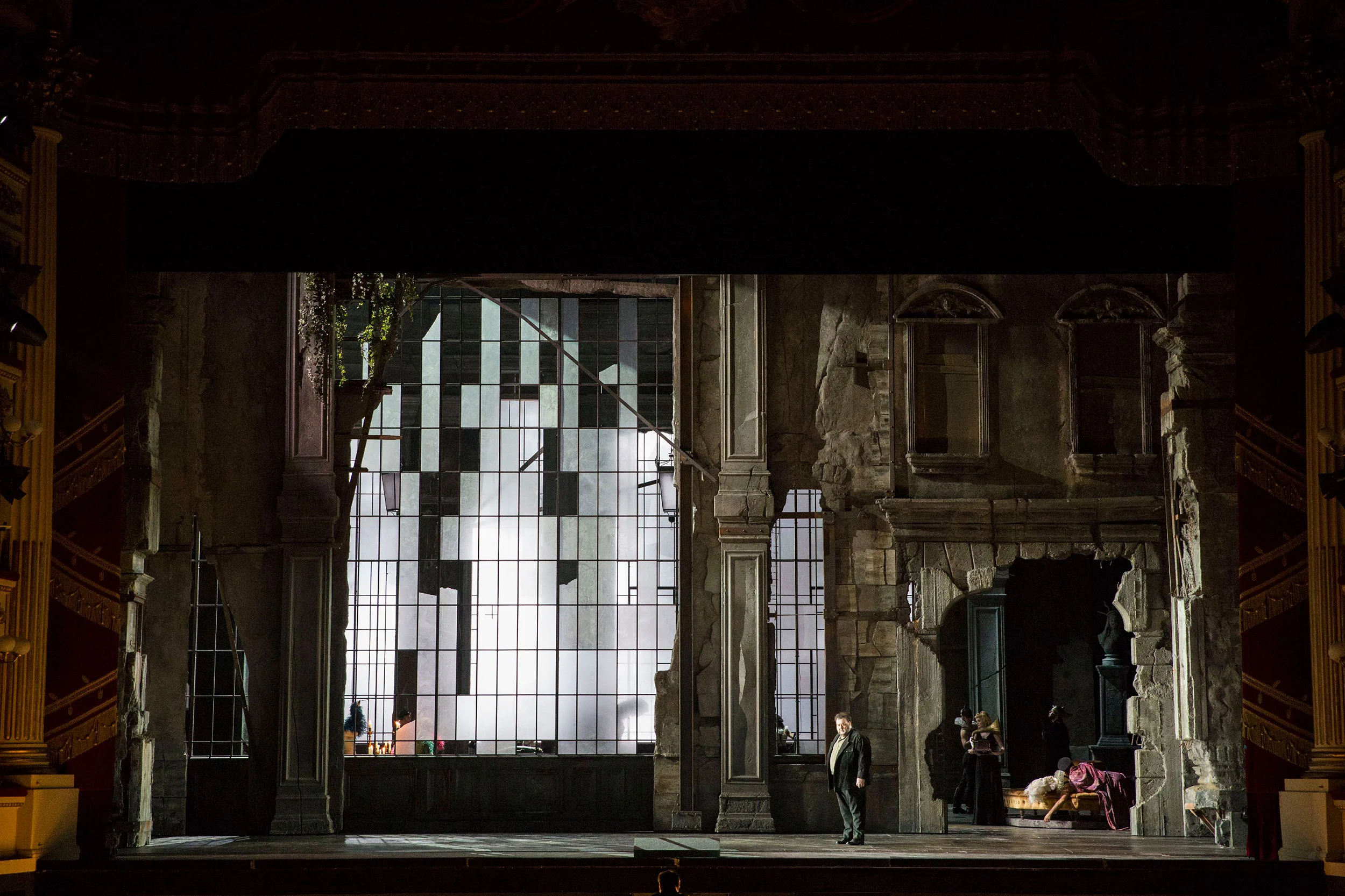 Cantante solo in un palazzo di pietra in rovina, dietro di lui un'alta vetrata rotta illuminata di bianco – Attila al Teatro alla Scala, Milano, Italia, 2018 – scenografia d'opera