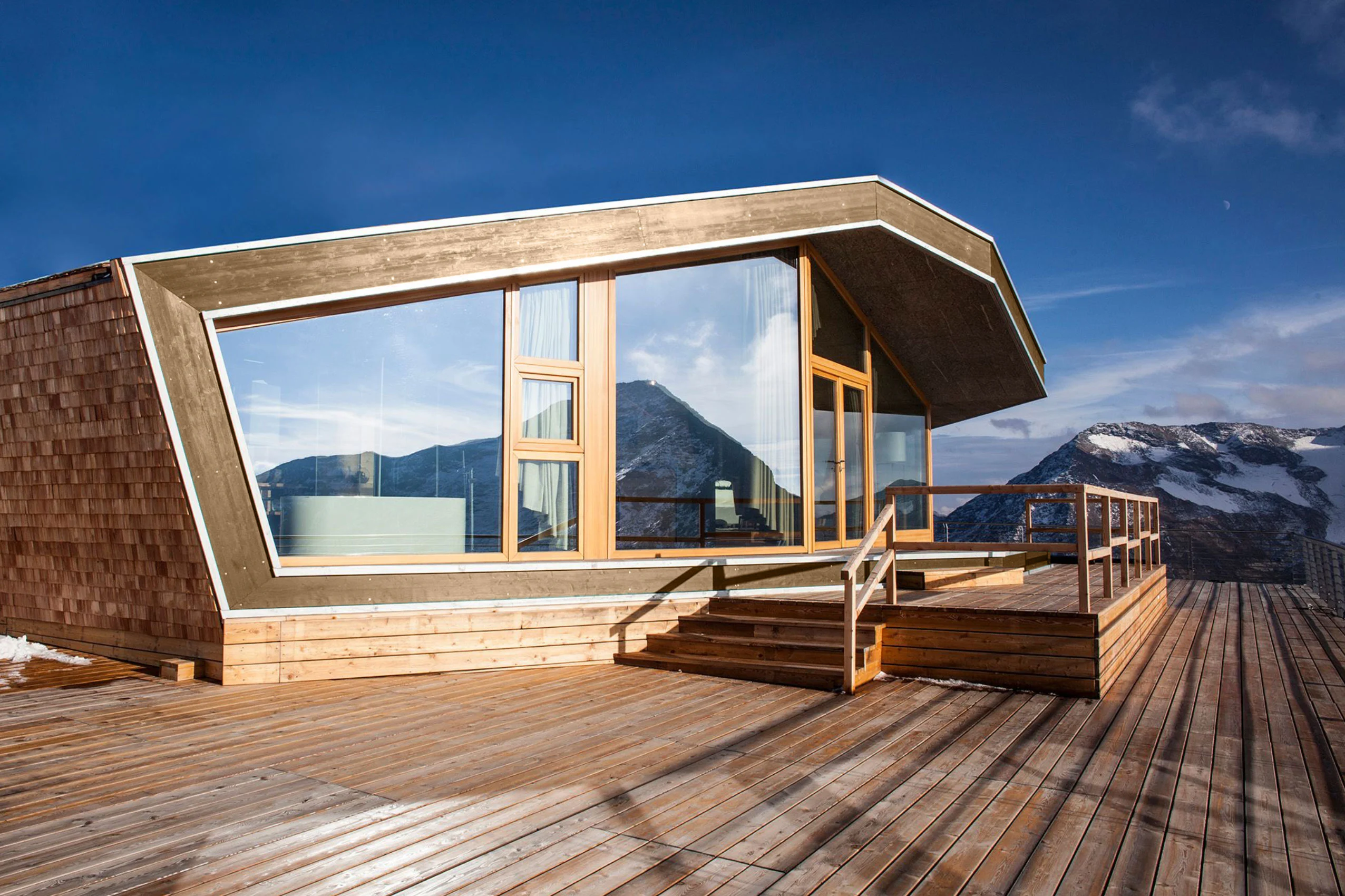 Esterno del Levissima 3000 Chalet: volume rivestito di scandole di legno con una grande vetrata e un deck in legno rivolto alle cime innevate – Levissima 3000 Chalet, Valdisotto, Italia, 2018 – architettura