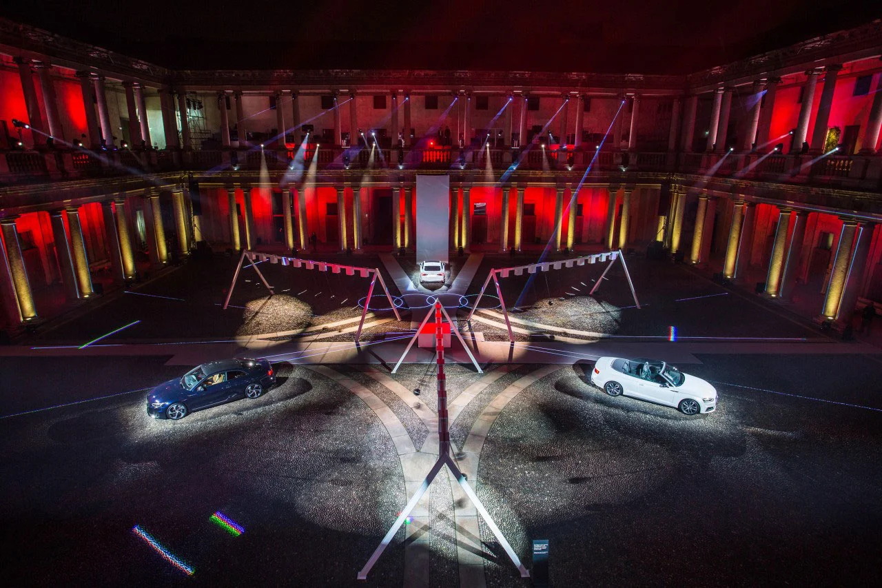 Vista dall'alto dell'installazione nel cortile: due decappottabili sotto i riflettori e alte strutture bianche ad altalena – Audi City Lab al Fuorisalone, Milano, Italia, 2017 – progettazione di eventi