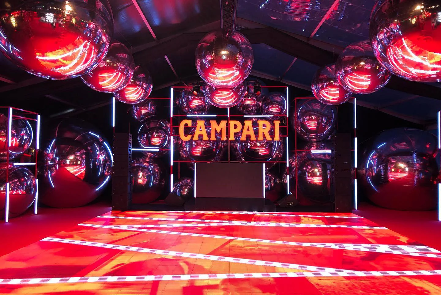 Pista da ballo del party Campari con pannelli LED rossi sotto enormi sfere a specchio, l'insegna Campari dietro la consolle del DJ – Campari al 75° Festival di Cannes, Francia, 2022 – progettazione di eventi