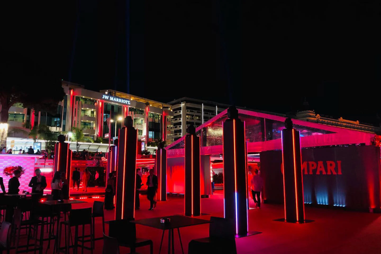 Vista notturna della terrazza Campari con colonne illuminate e un padiglione in luce rossa, la facciata dell'hotel sullo sfondo – Campari al 75° Festival di Cannes, Francia, 2022 – progettazione di eventi