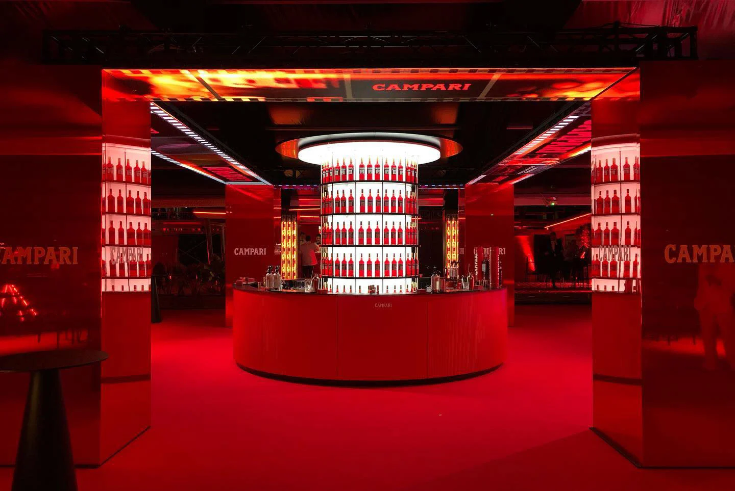 Vista frontale del bar rotondo Campari tra colonne rosse e un architrave LED con il nome del marchio – Campari al 75° Festival di Cannes, Francia, 2022 – progettazione di eventi