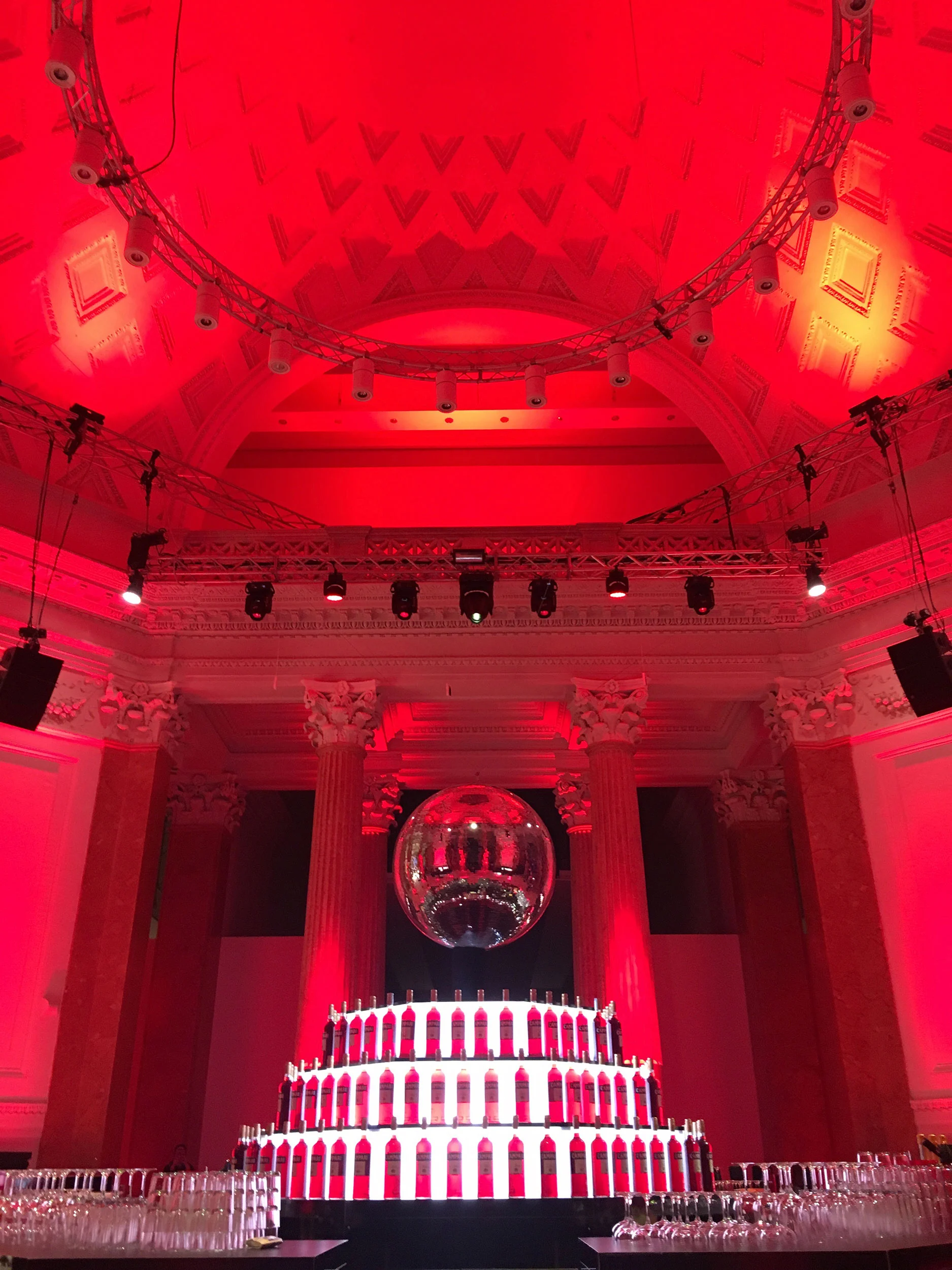 Sala a cupola in luce rossa con una palla a specchi sopra un espositore a gradoni di bottiglie Campari – Campari Red Diaries, Milano, Italia, 2017 – progettazione di eventi
