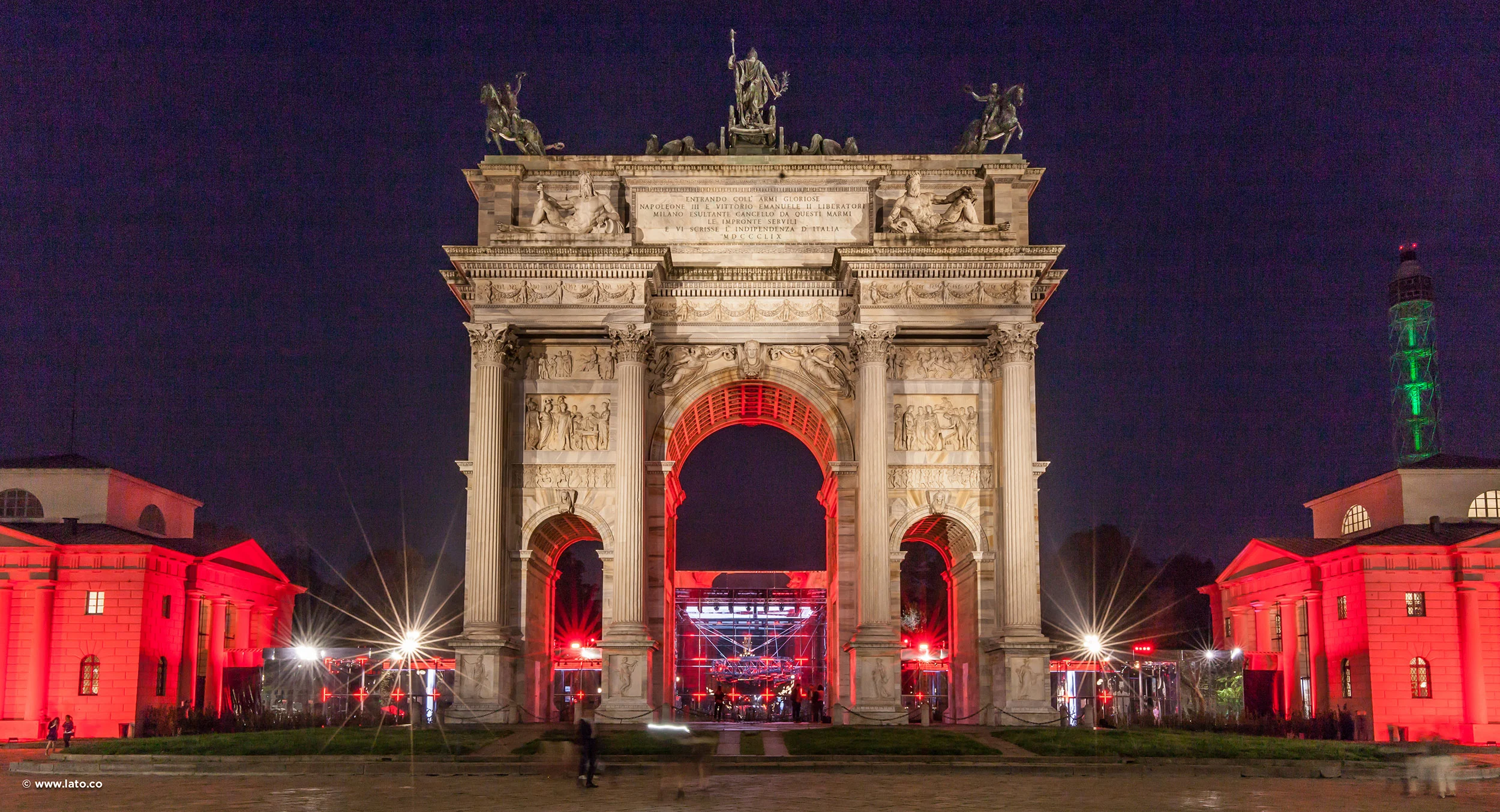 Vista notturna frontale dell'Arco della Pace con il padiglione illuminato di rosso inquadrato nell'arco centrale – Cartier The Legendary Thrill, Milano, Italia, 2018 – progettazione di eventi