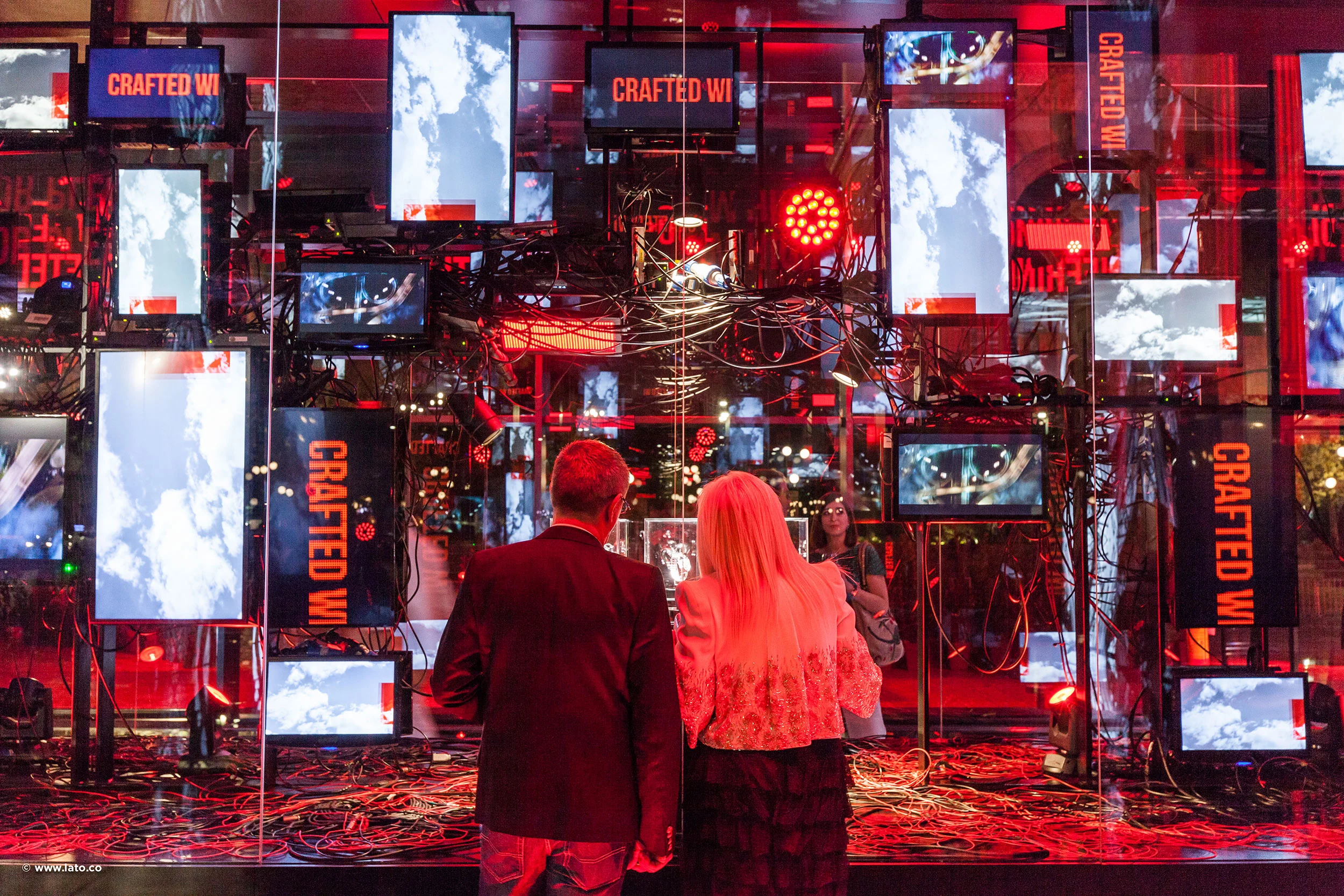 Visitatori davanti a una parete di schermi illuminata di rosso con nuvole, striscioni Crafted Wi... e cavi – Cartier The Legendary Thrill, Milano, Italia, 2018 – progettazione di eventi