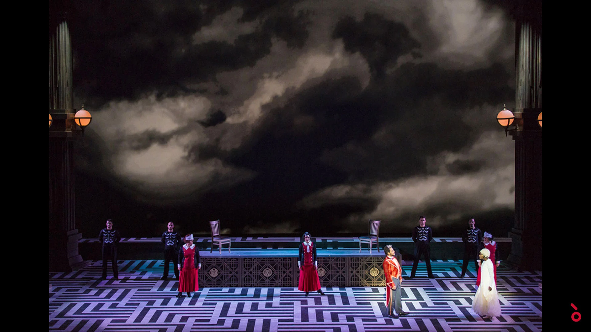 Artisti allineati su un pavimento a labirinto sotto un'enorme proiezione di nubi temporalesche scure – The Opera! alla Royal Opera House Muscat, Oman, 2019 – scenografia