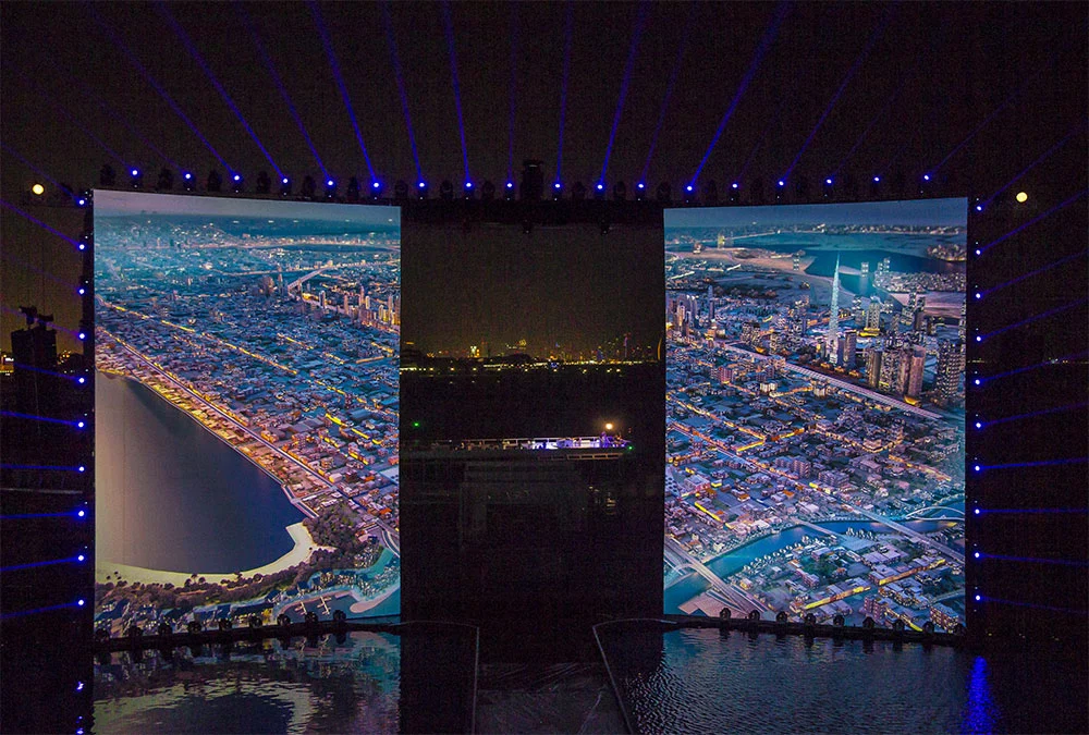 Due schermi laterali con viste aeree notturne della costa di Dubai, tra loro le luci della città – Cerimonia di apertura del Dubai Water Canal, Emirati Arabi Uniti, 2016 – progettazione di eventi