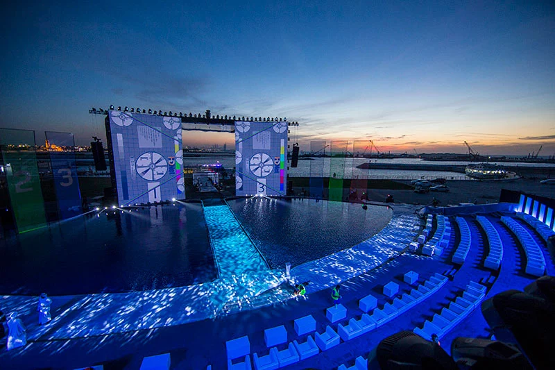 Prove al tramonto: schermi con immagini di test, palco d'acqua illuminato e sedute bianche vuote – Cerimonia di apertura del Dubai Water Canal, Emirati Arabi Uniti, 2016 – progettazione di eventi