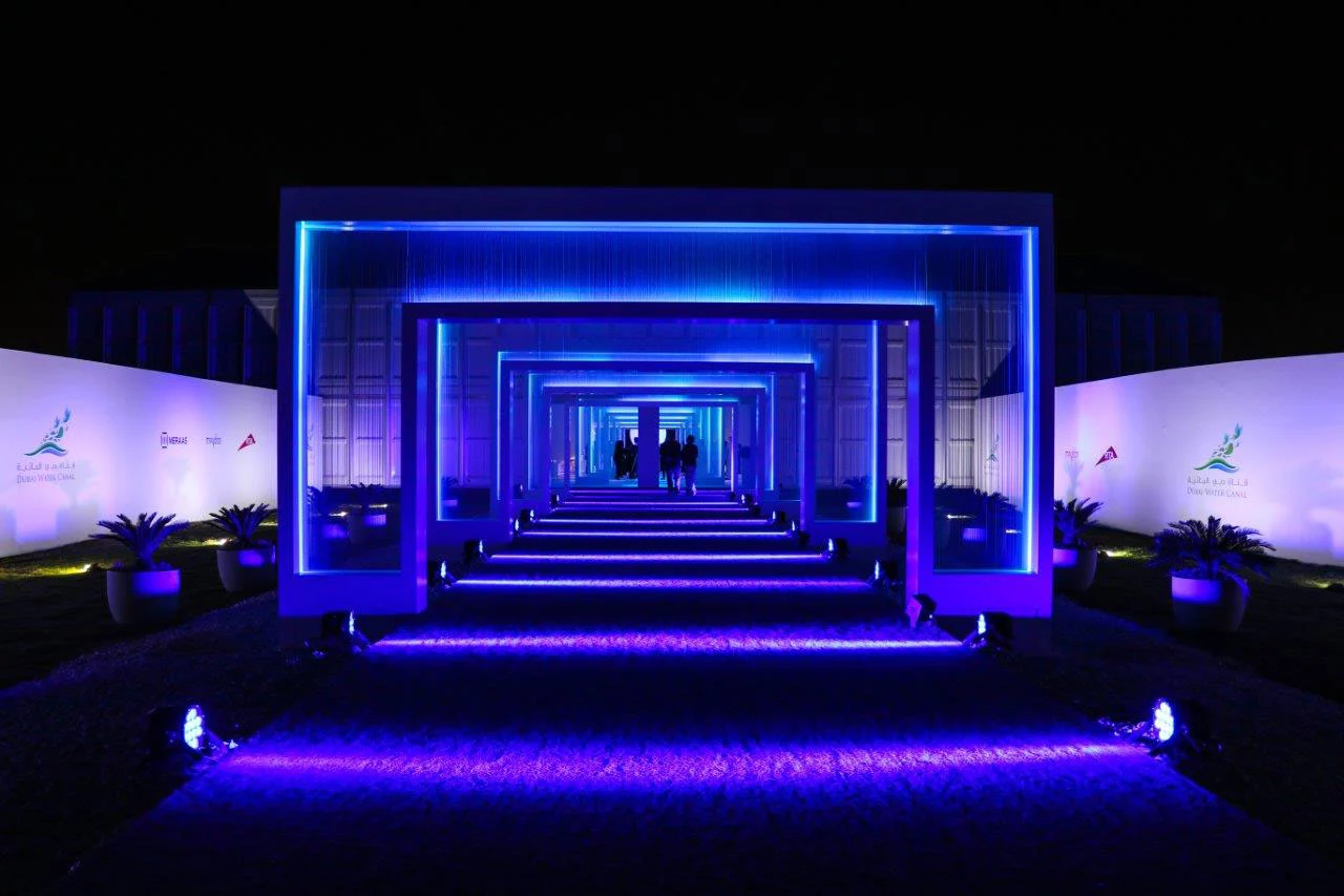 Ingresso degli ospiti attraverso un tunnel di cornici concentriche illuminate di blu, tra palme e pareti bianche – Cerimonia di apertura del Dubai Water Canal, Emirati Arabi Uniti, 2016 – progettazione di eventi