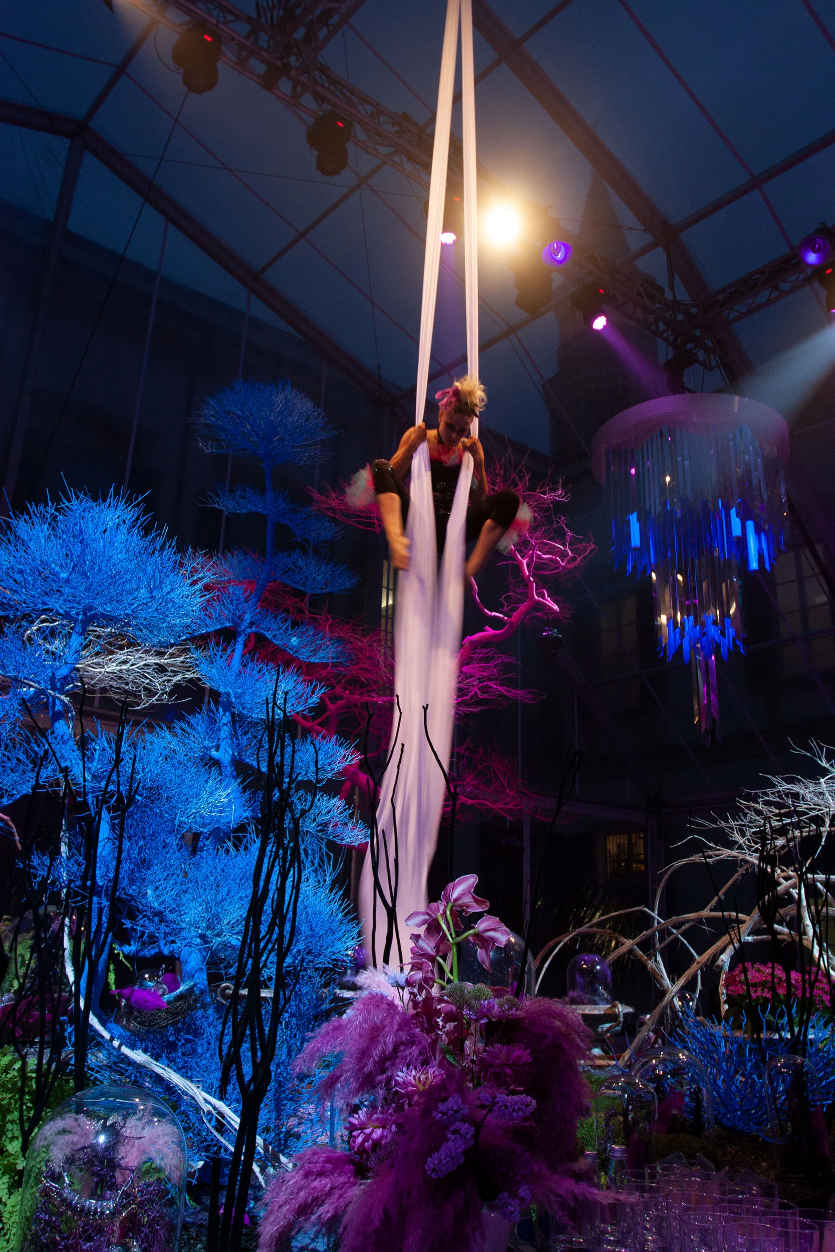 Acrobata aerea su tessuti bianchi sopra alberi piumati blu e viola e installazioni floreali – Swarovski Fashionation Party a Palazzo Reale, Milano, Italia, 2011 – progettazione di eventi