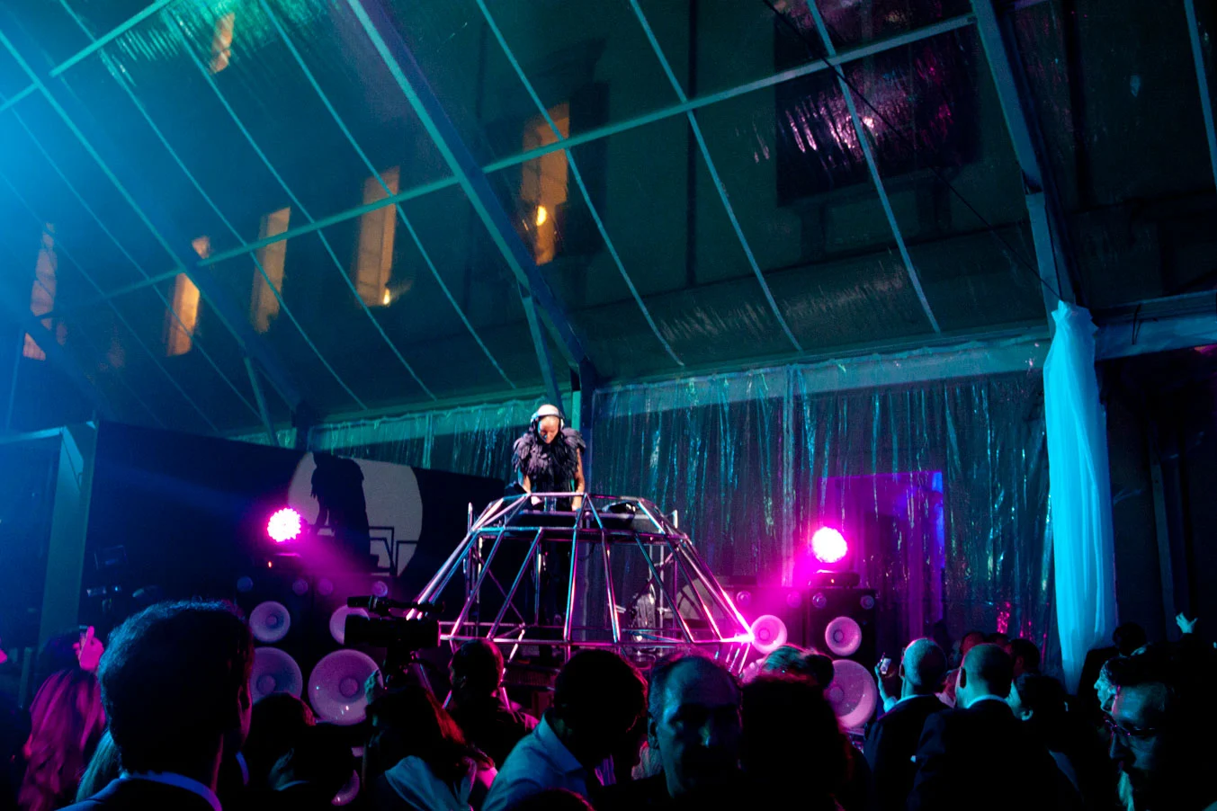 DJ che suona da una consolle a telaio metallico sotto una tenda trasparente, pubblico illuminato di rosa e verde acqua – Swarovski Fashionation Party a Palazzo Reale, Milano, Italia, 2011 – progettazione di eventi