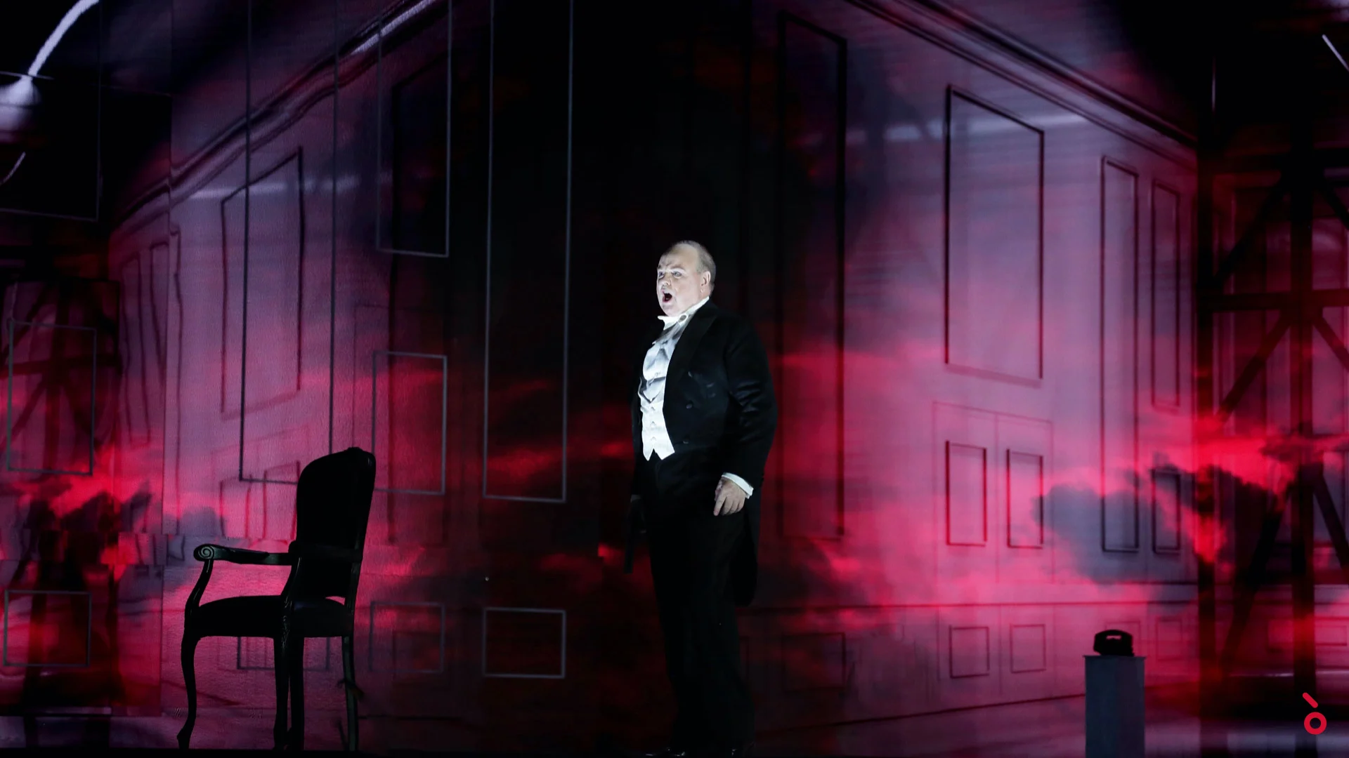 Cantante in frac accanto a una sedia vuota, le pareti del palazzo proiettate in una nebbia rossa alle sue spalle – Elisabetta, Regina d'Inghilterra al Rossini Opera Festival, Pesaro, Italia, 2021 – scenografia d'opera