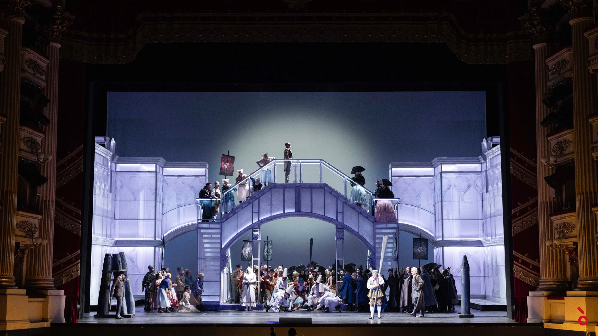 Coro su una doppia scalinata e un ponte chiari sotto un occhio di bue, un solista in proscenio – La Gioconda al Teatro alla Scala, Milano, Italia, 2022 – scenografia d'opera