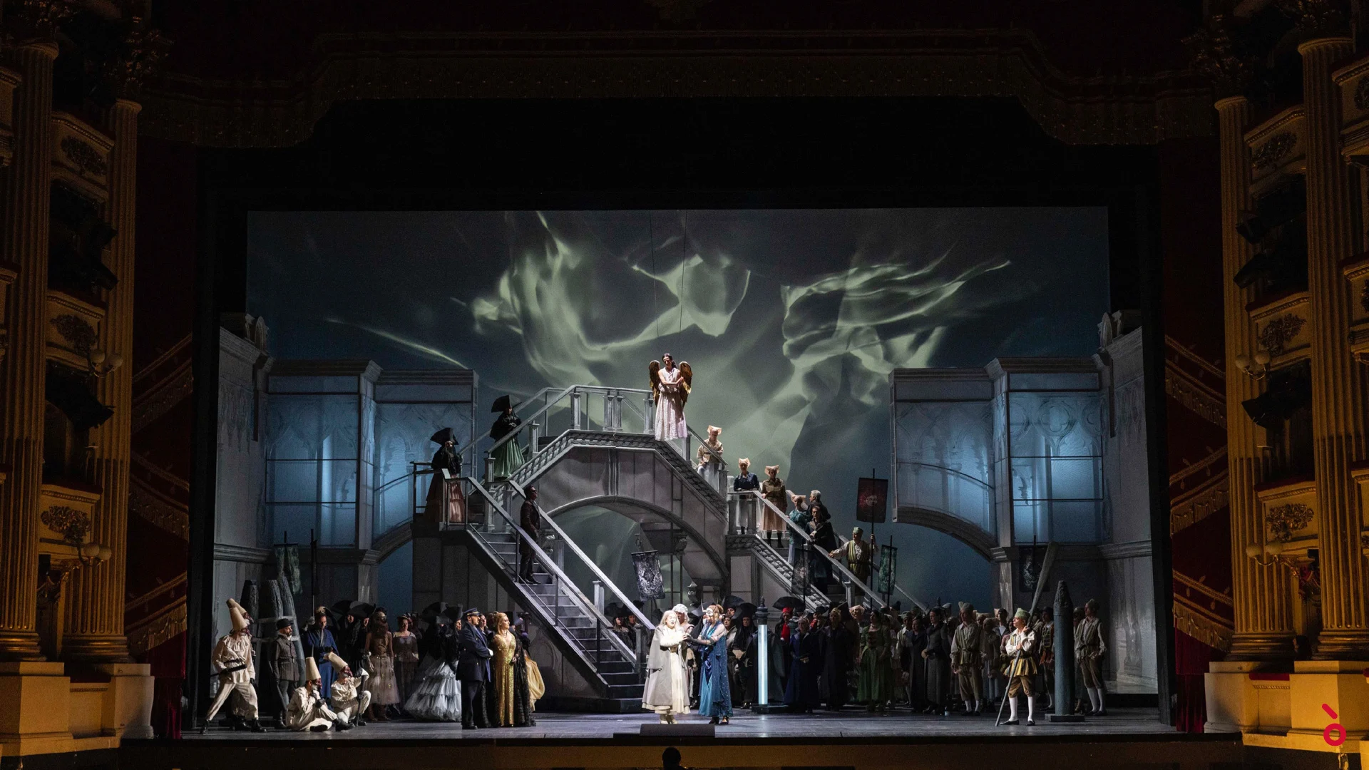 Coro affollato su una grande scenografia a doppia scalinata, con proiezioni di volute di fumo sul fondale – La Gioconda al Teatro alla Scala, Milano, Italia, 2022 – scenografia d'opera