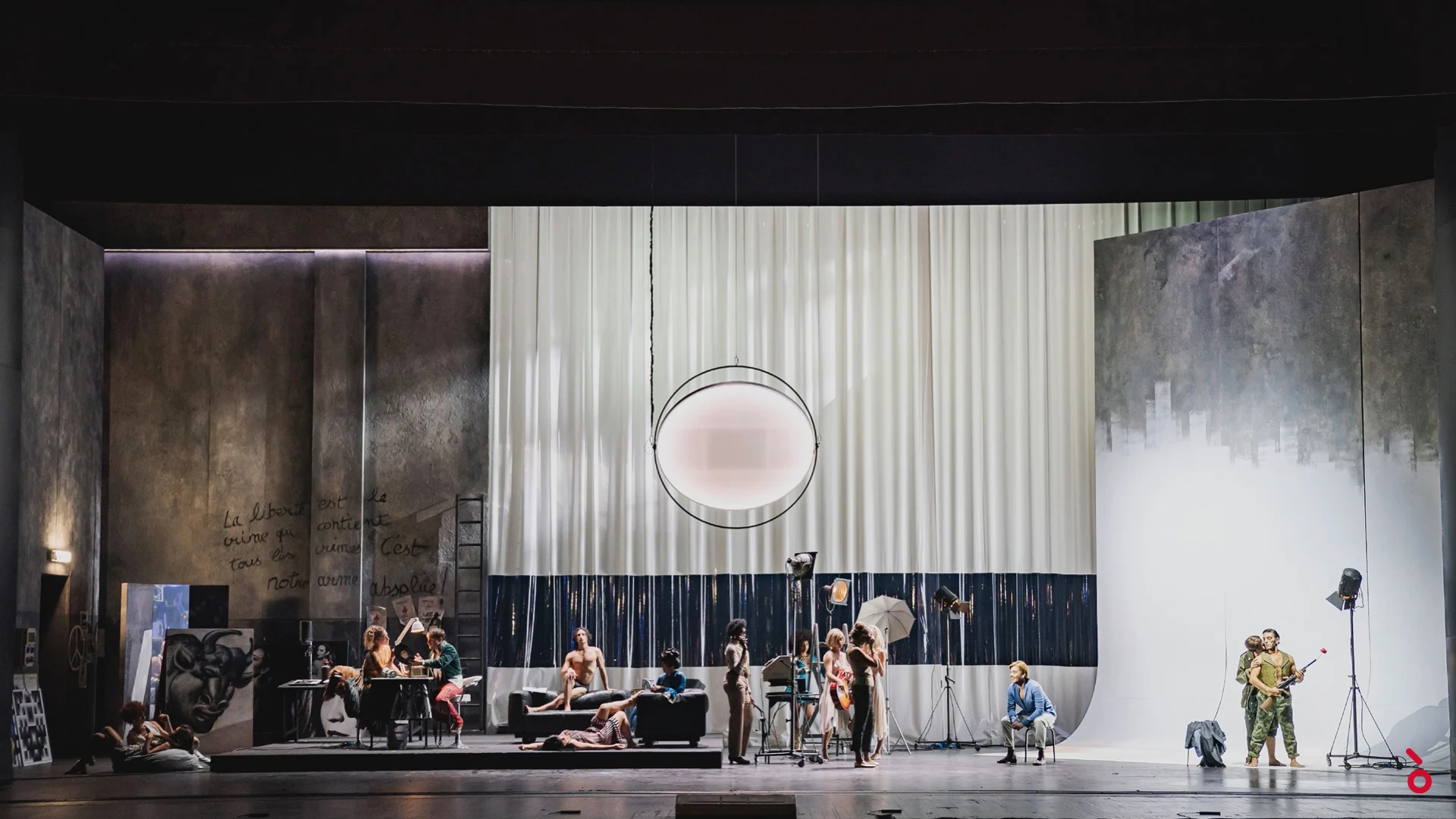 Vista d'insieme di una scenografia da studio fotografico con drappi bianchi, una luce rotonda e artisti in posa sui divani – La Traviata al Maggio Musicale Fiorentino, Firenze, Italia, 2022 – scenografia d'opera