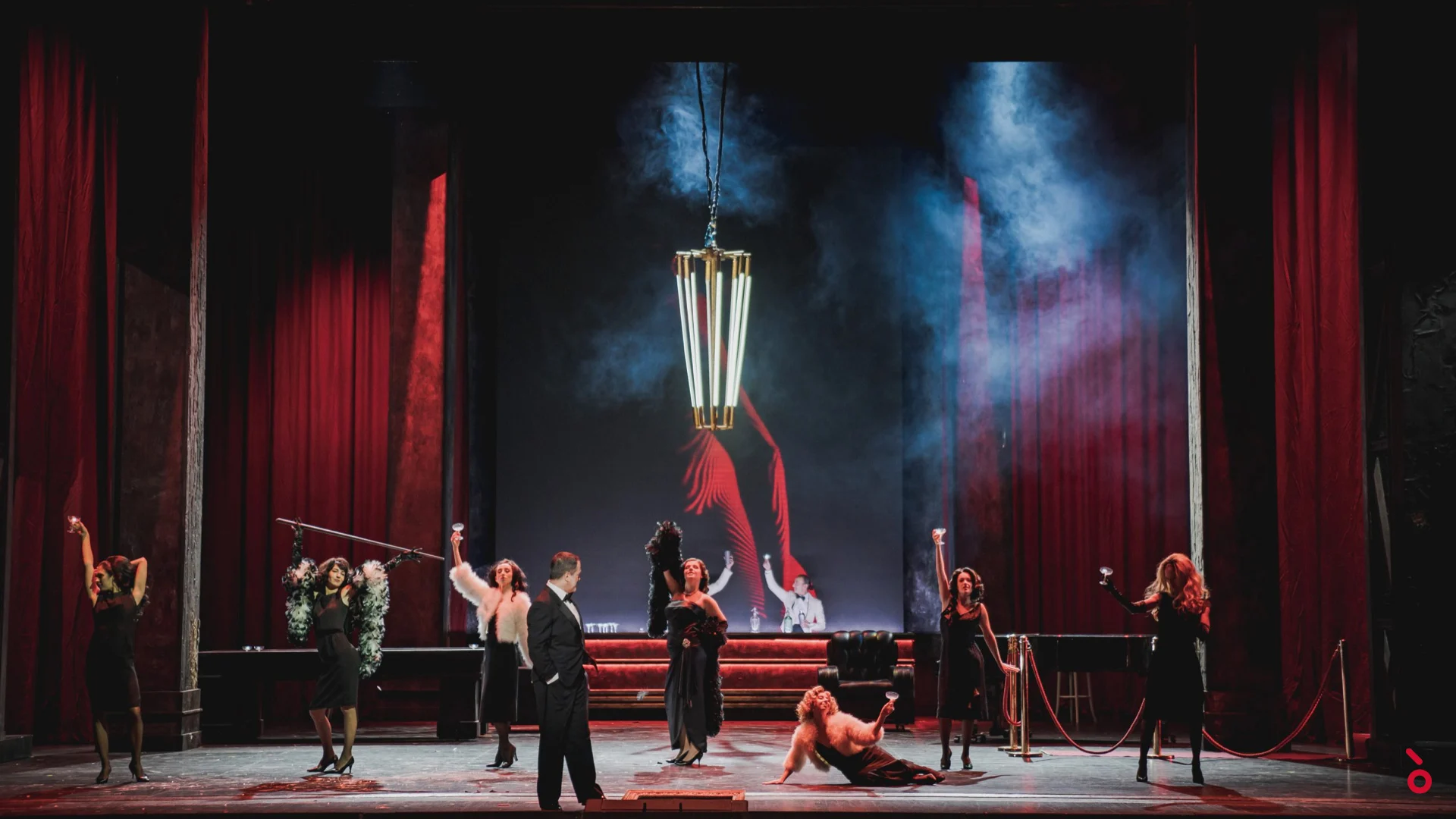 Scena di cabaret tra sipari di velluto rosso, ballerini in nero attorno a una lanterna sospesa – Rigoletto al Maggio Musicale Fiorentino, Firenze, Italia, 2021 – scenografia d'opera