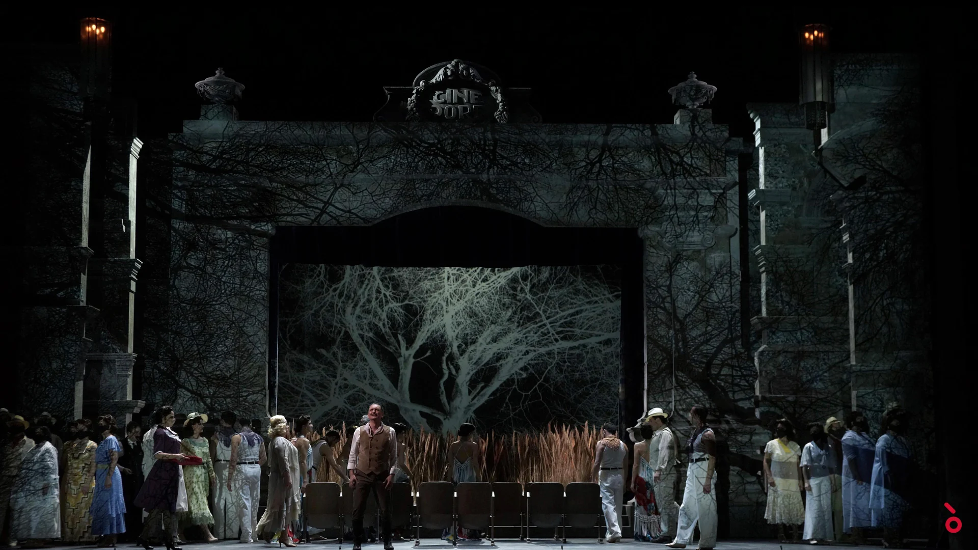 Coro davanti all'ornata facciata del cinema, un albero spoglio proiettato nell'arco sopra file di poltrone – Luisa Fernanda al Teatro de la Zarzuela, Madrid, Spagna, 2021 – scenografia d'opera
