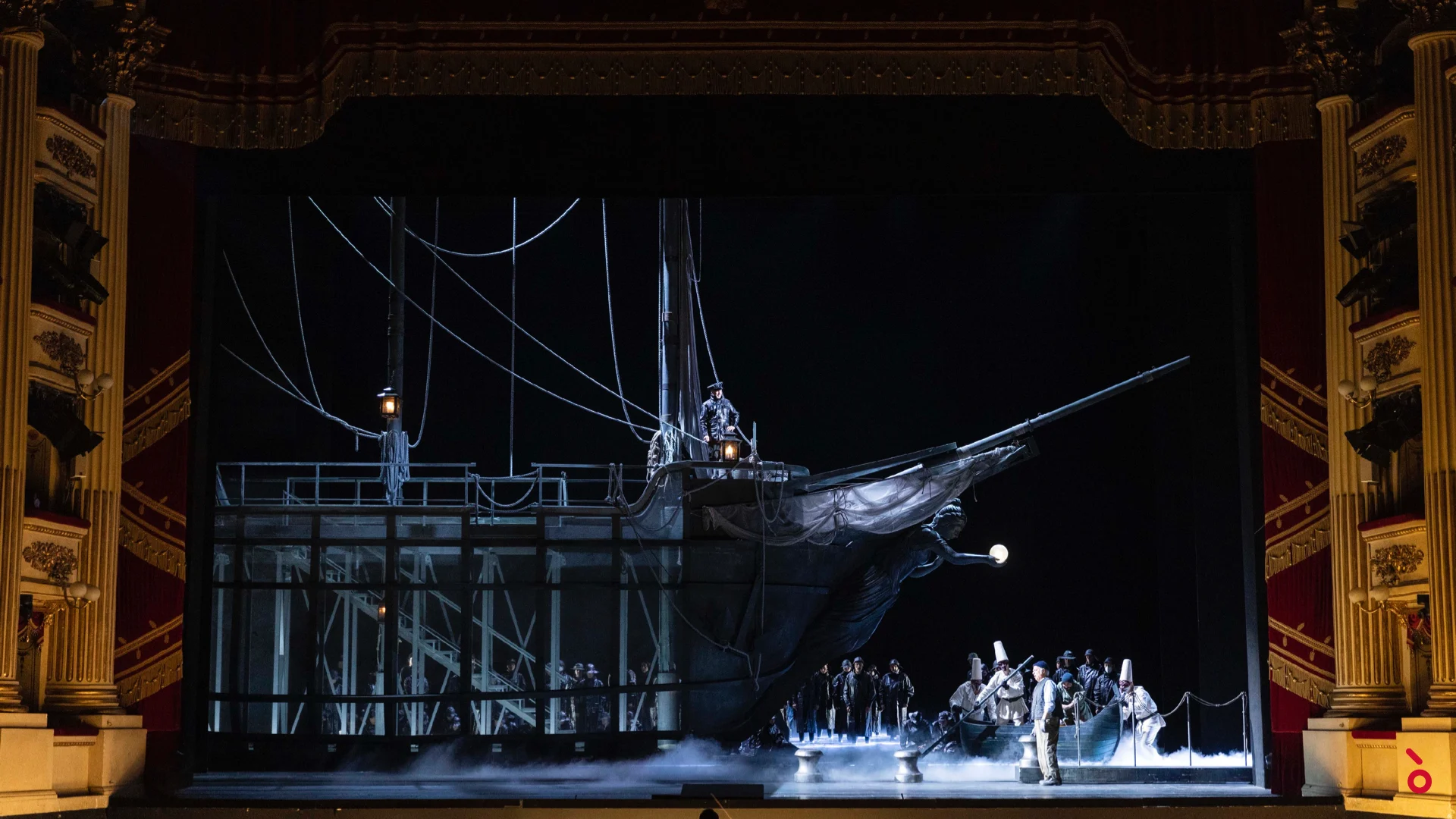 La scenografia del galeone sul palco della Scala: una nave scura con alti alberi e sartiame sull'acqua nebbiosa, il coro a prua – La Gioconda al Teatro alla Scala, Milano, Italia, 2022 – scenografia d'opera
