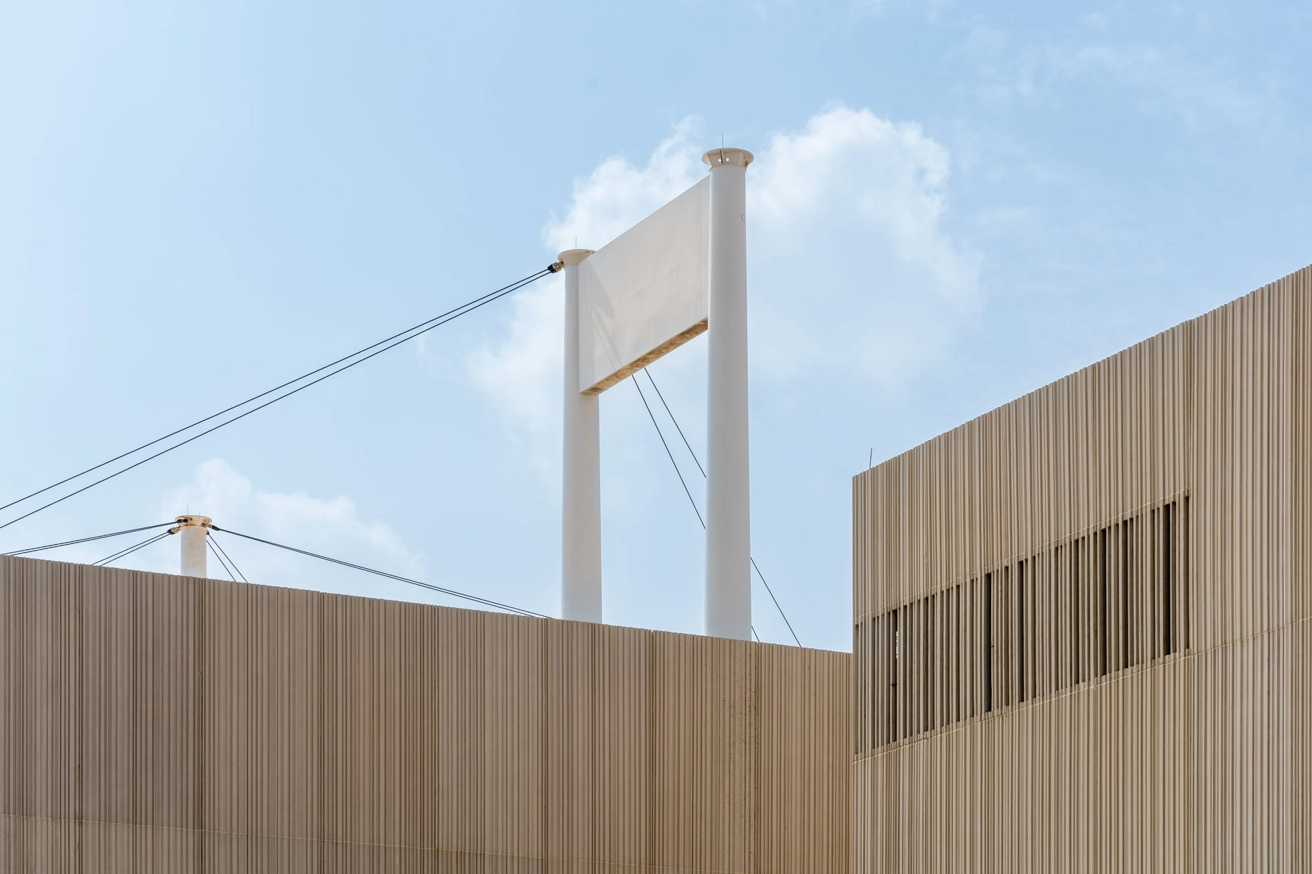 Pareti a listelli del padiglione contro il cielo, con un pilone bianco delle tende e i suoi cavi che si alzano dietro – Biennale delle Arti Islamiche, Jeddah, Arabia Saudita, 2023 – architettura
