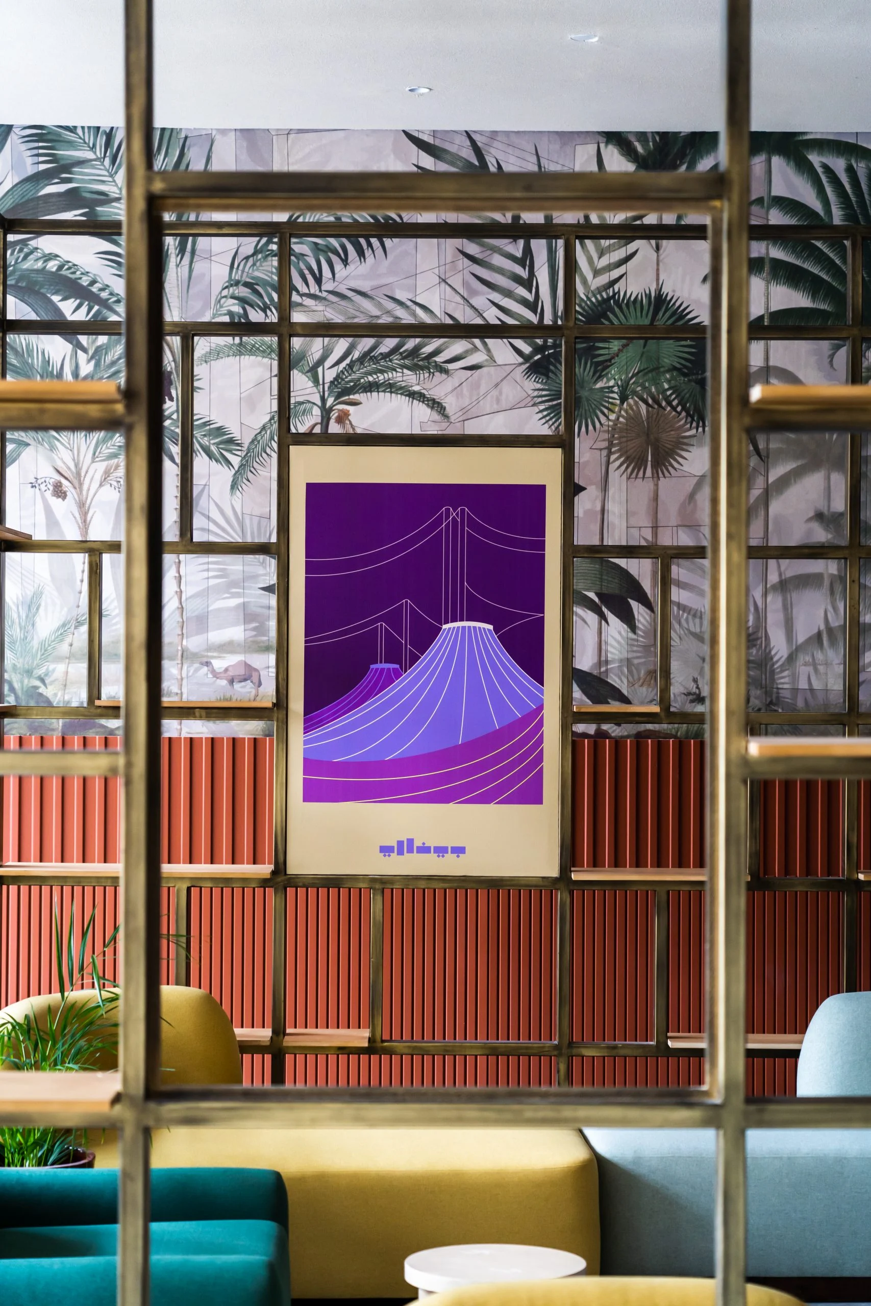 Poster viola delle tende dell'Hajj Terminal in una scaffalatura in ottone contro una carta da parati a palme – Biennale delle Arti Islamiche, Jeddah, Arabia Saudita, 2023 – architettura