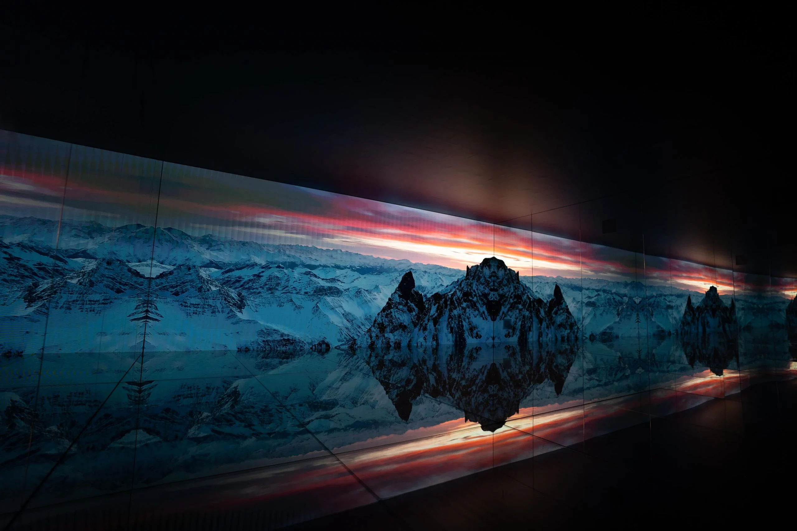 Lunga parete LED con vette montuose sotto un cielo rosso al tramonto, riflessa nel pavimento a specchio – Mont Blanc Infinity Room allo Skyway, Courmayeur, Italia, 2023 – progettazione di installazioni