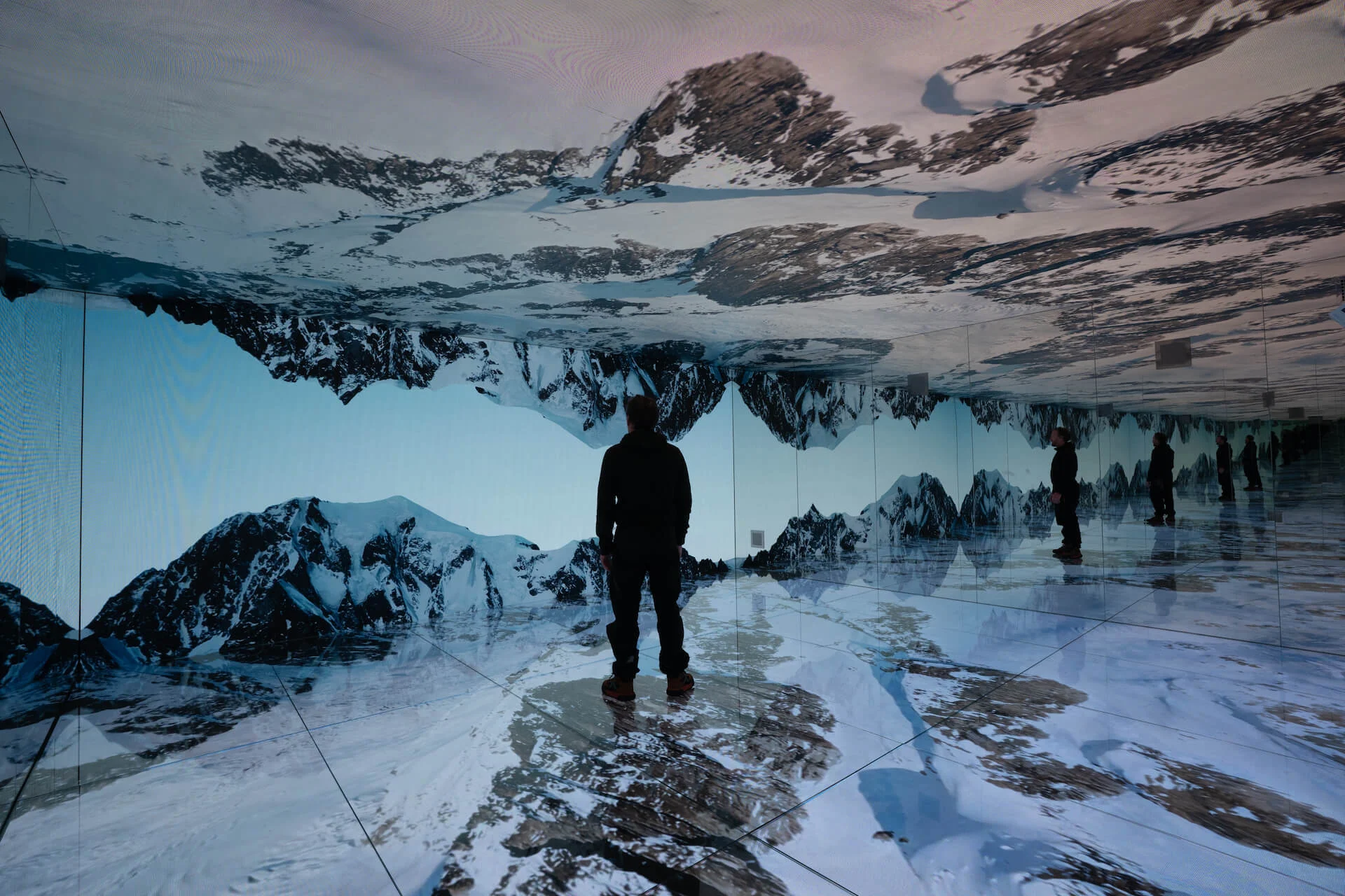 Visitatore nella Mont Blanc Infinity Room, circondato da pareti LED e specchi con vette innevate – Mont Blanc Infinity Room allo Skyway, Courmayeur, Italia, 2023 – progettazione di installazioni