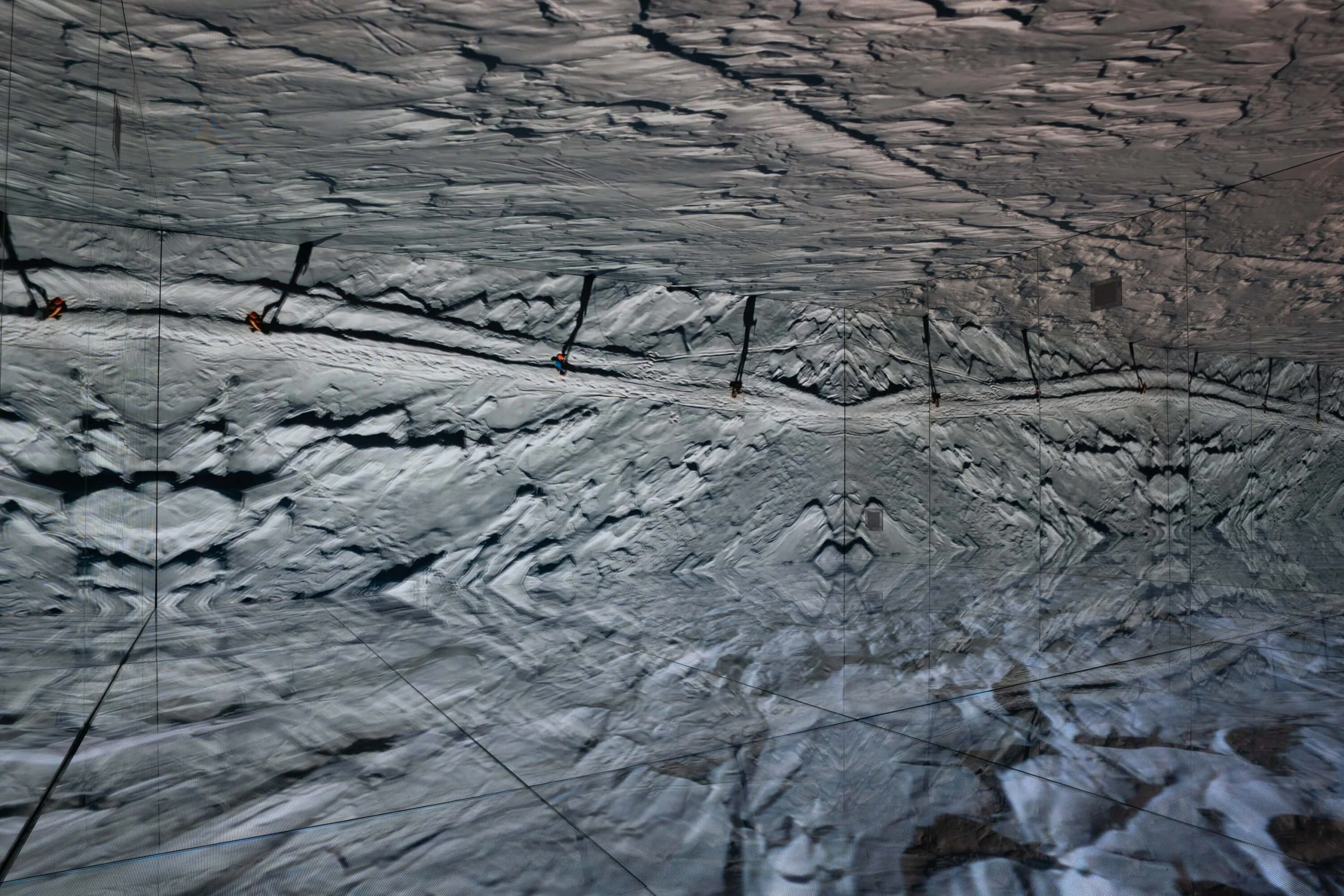 Riprese aeree di creste rocciose innevate sul soffitto e sulle pareti LED, riflesse in un disegno simmetrico – Mont Blanc Infinity Room allo Skyway, Courmayeur, Italia, 2023 – progettazione di installazioni