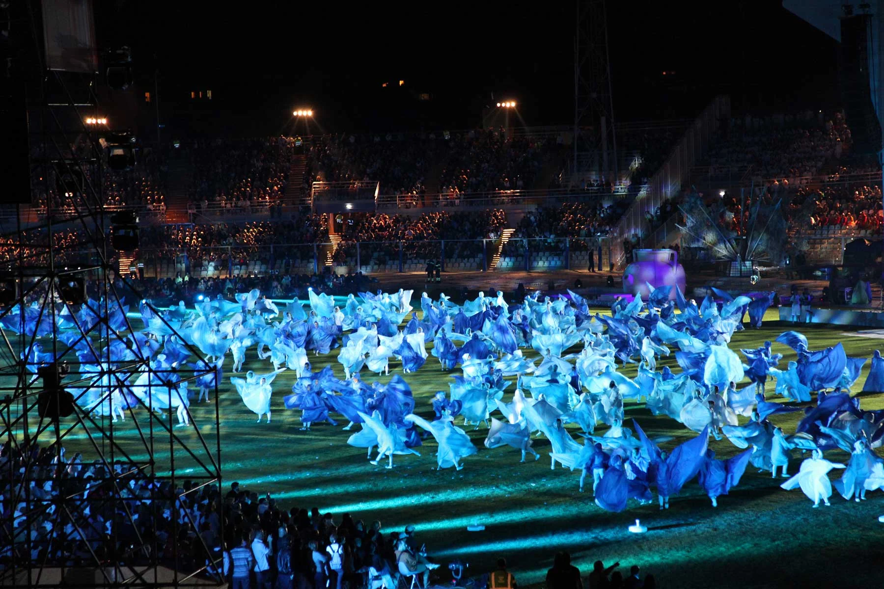 Centinaia di artisti in fluenti costumi blu e bianchi che coprono il campo dello stadio – Cerimonia di apertura dei Giochi del Mediterraneo Pescara 2009, Italia, 2019 – progettazione di eventi