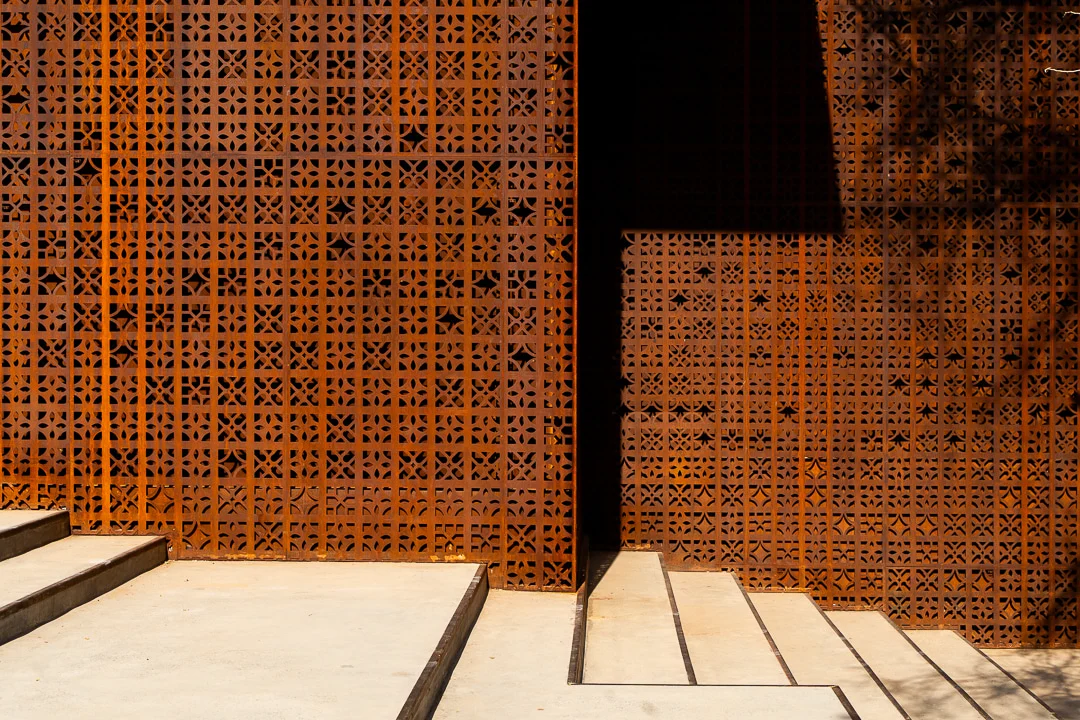 Dettaglio del motivo geometrico dello schermo forato sopra gradini in cemento, tra sole e ombra – Design Space AlUla, Arabia Saudita, 2024 – architettura