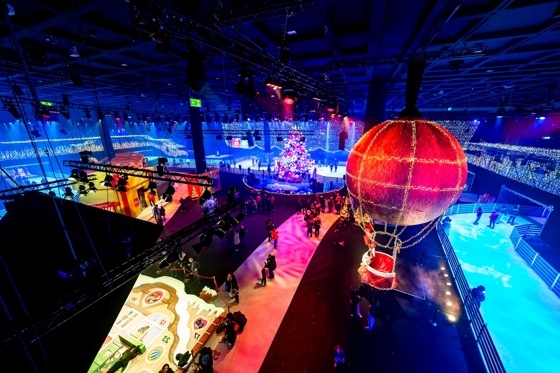 Vista aerea del padiglione con una mongolfiera illuminata, la pista di pattinaggio, l'albero di Natale e i visitatori – A Christmas Magic all'Allianz MiCo, Milano, Italia, 2023 – progettazione di eventi