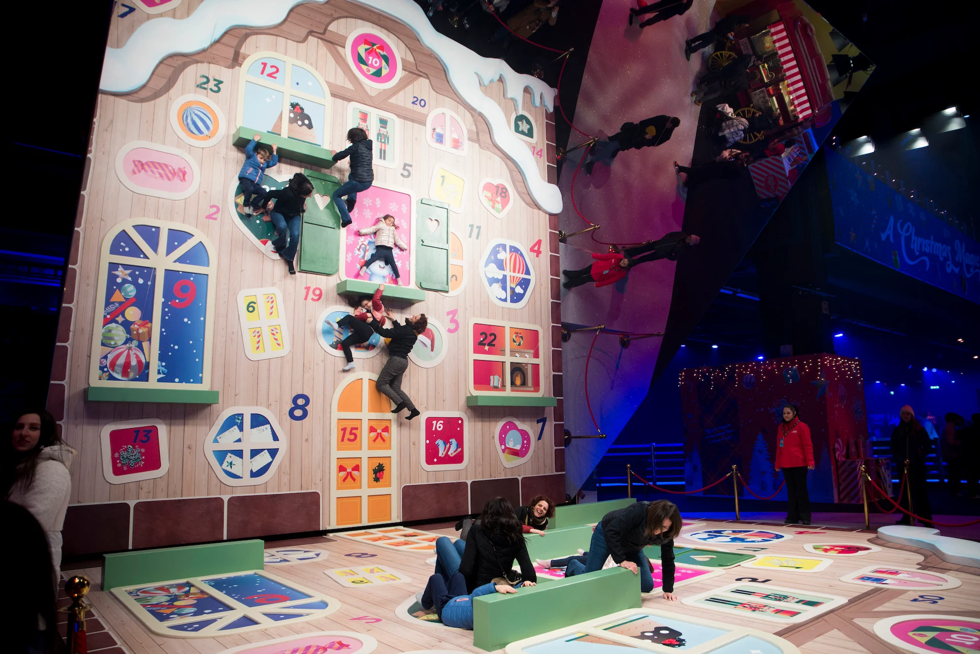 Visitatori in posa su una gigantesca facciata a calendario dell'Avvento stesa a terra, con uno specchio che crea un'illusione – A Christmas Magic all'Allianz MiCo, Milano, Italia, 2023 – progettazione di eventi
